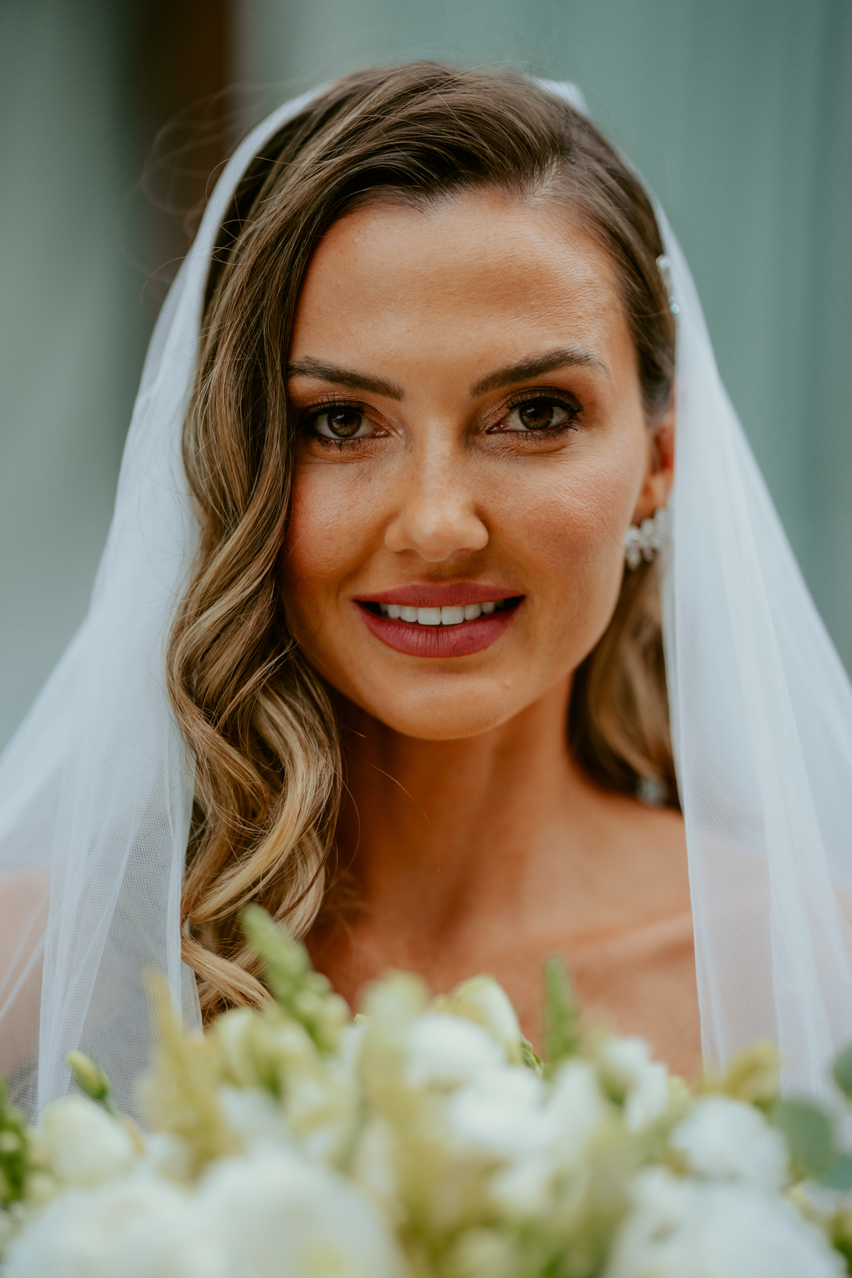 Noiva em frente ao chalé no Refúgio dos Lagos em Massaranduba com véu ao vento, cenário arquitetônico moderno e natureza ao redor, ideal para casamentos ao ar livre.