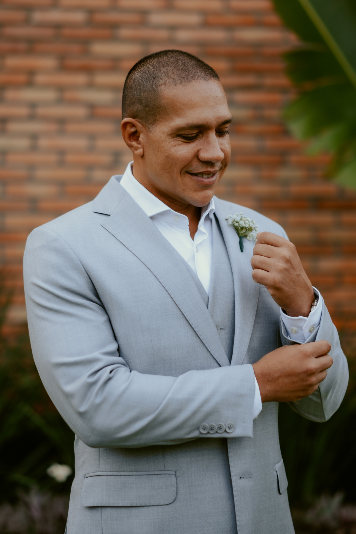 Noivo Tiago se arrumando com terno claro durante casamento em Massaranduba no Refúgio dos Lagos, momento de preparação elegante antes da cerimônia ao ar livre.