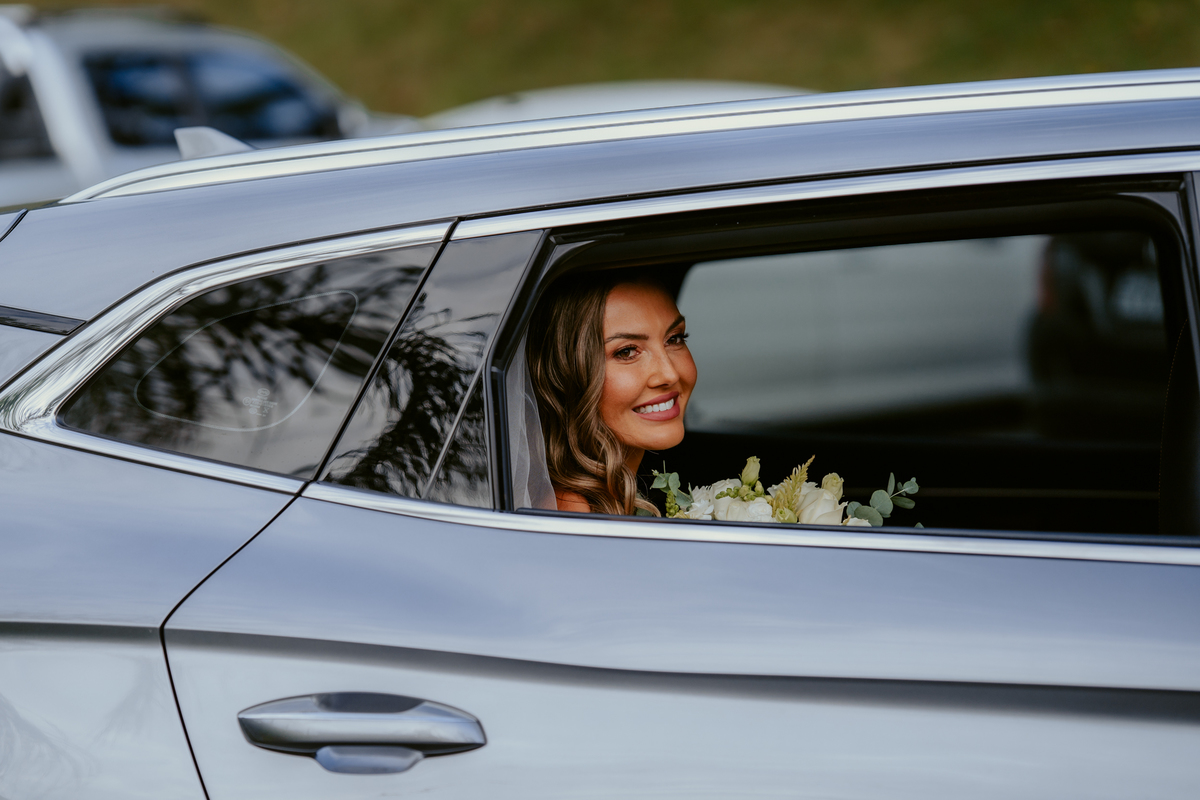 Noiva entrando na cerimônia acompanhada de familiares em casamento ao ar livre no Refúgio dos Lagos em Massaranduba, com convidados emocionados e cenário natural.