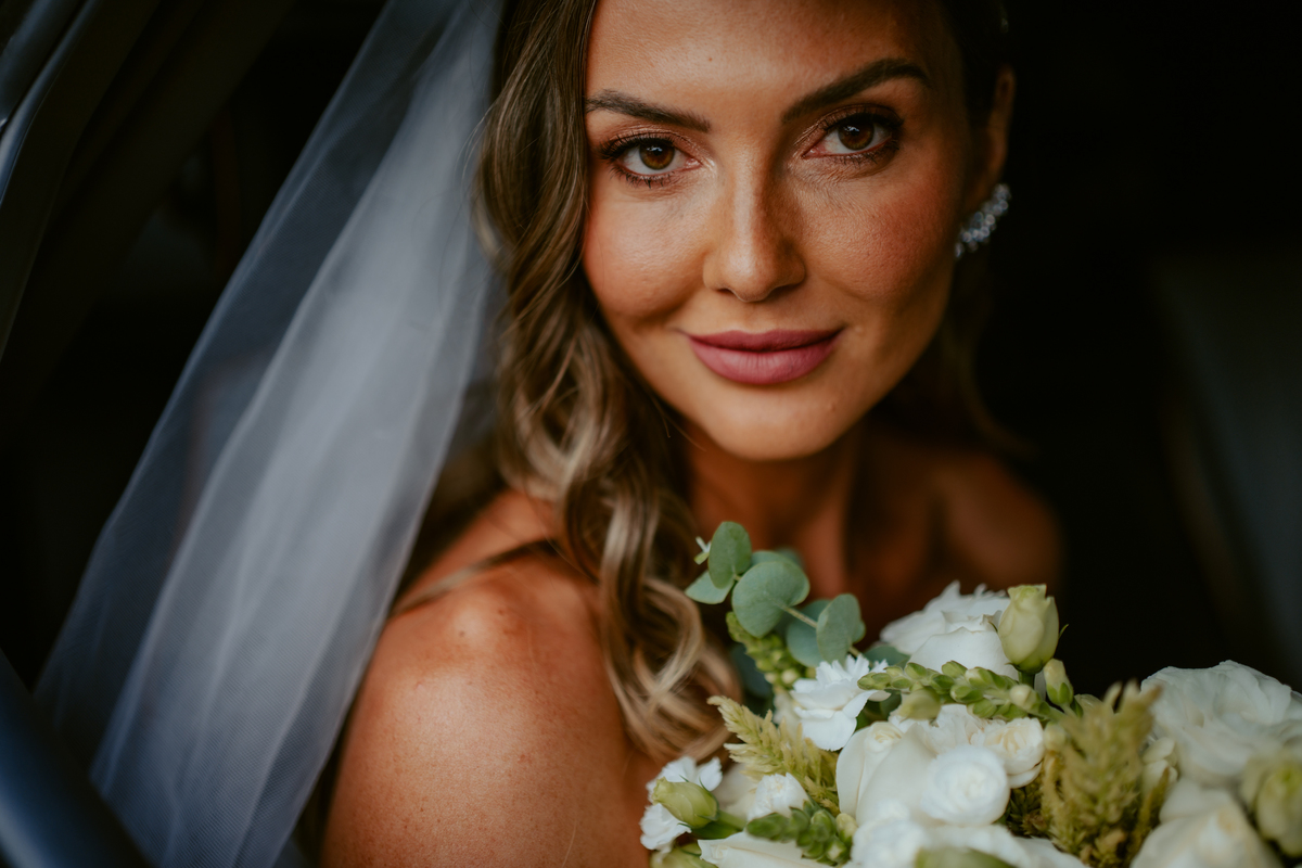 Noiva entrando na cerimônia acompanhada de familiares em casamento ao ar livre no Refúgio dos Lagos em Massaranduba, com convidados emocionados e cenário natural.