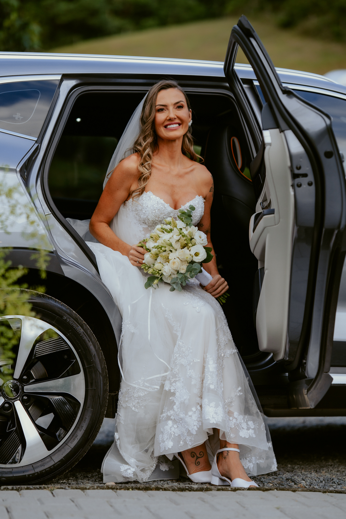 Noiva entrando na cerimônia acompanhada de familiares em casamento ao ar livre no Refúgio dos Lagos em Massaranduba, com convidados emocionados e cenário natural.