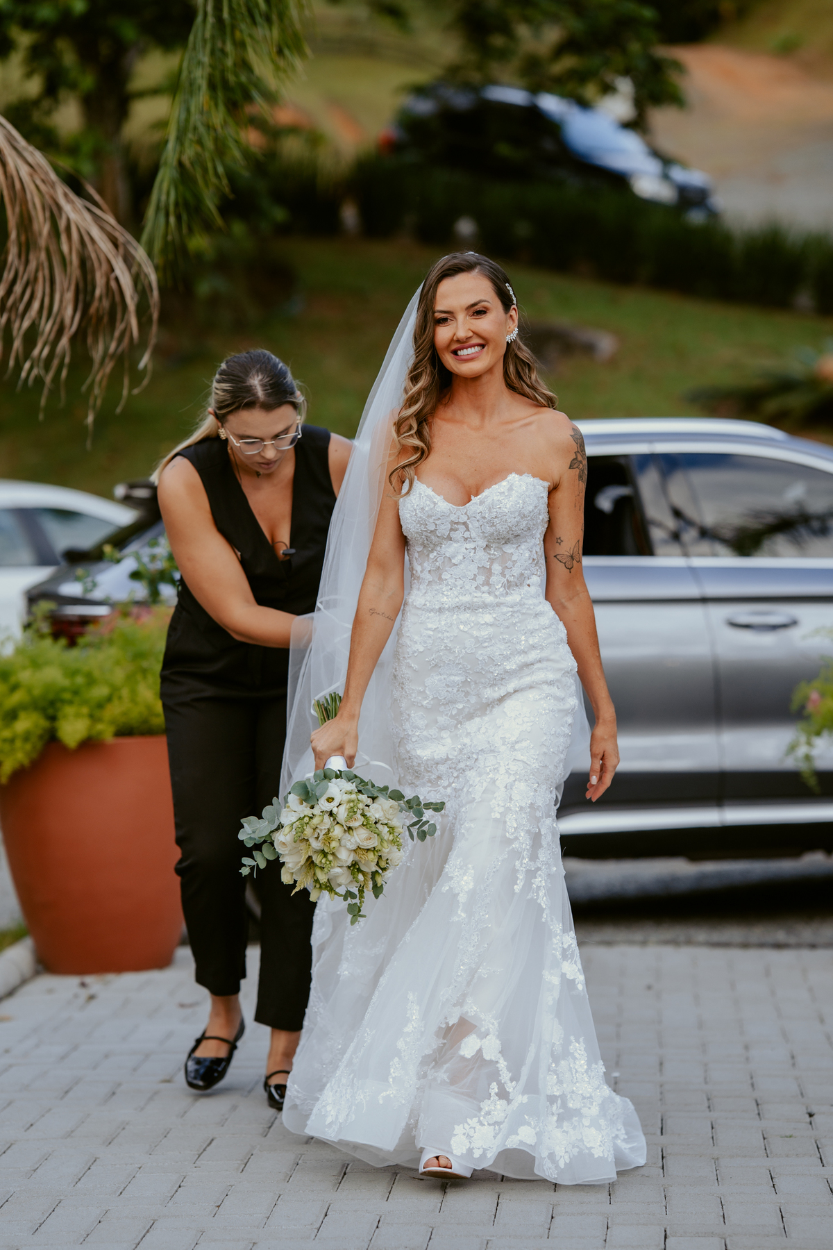 Noiva entrando na cerimônia acompanhada de familiares em casamento ao ar livre no Refúgio dos Lagos em Massaranduba, com convidados emocionados e cenário natural.