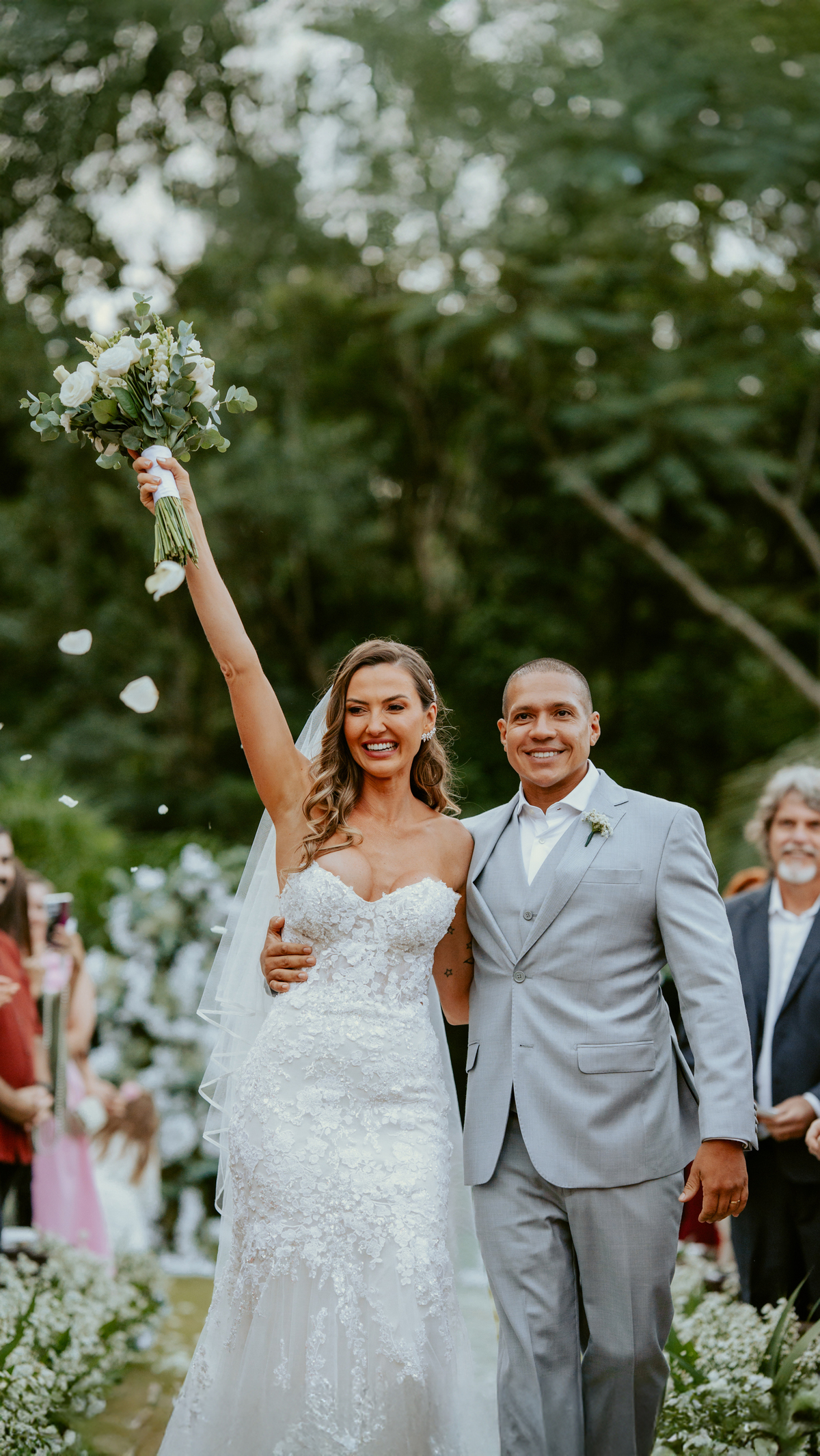 Saída dos noivos após cerimônia de casamento em Massaranduba no Refúgio dos Lagos com pétalas e celebração dos convidados.