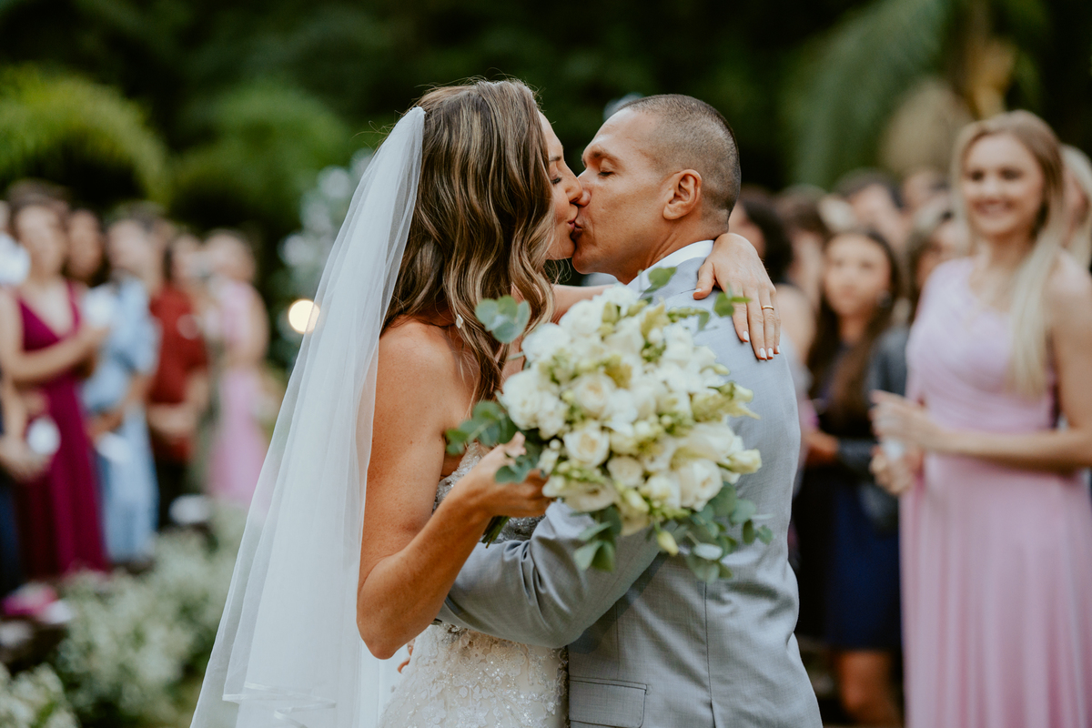Saída dos noivos após cerimônia de casamento em Massaranduba no Refúgio dos Lagos com pétalas e celebração dos convidados.
