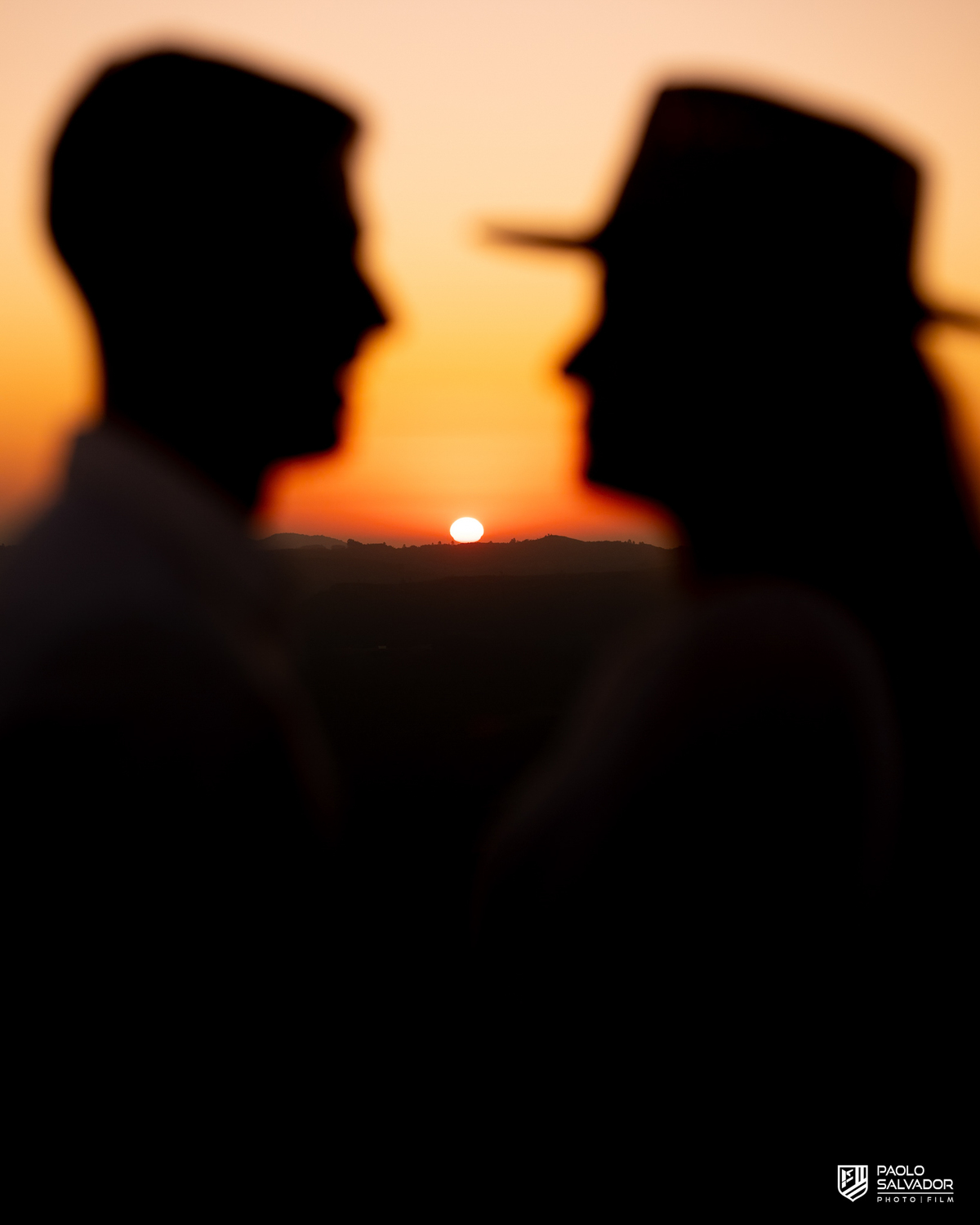 ilhueta do casal ao pôr do sol em ensaio pré-wedding na Serra Catarinense, com montanhas ao fundo e luz intensa criando efeito artístico.