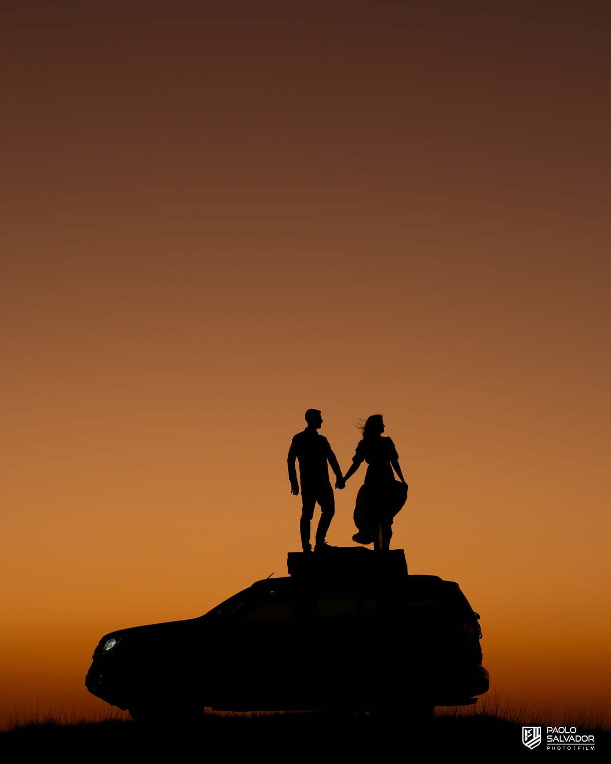 ilhueta do casal ao pôr do sol em ensaio pré-wedding na Serra Catarinense, com montanhas ao fundo e luz intensa criando efeito artístico.