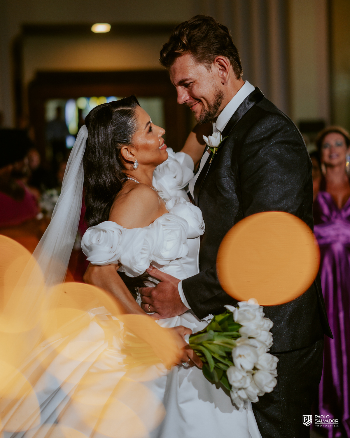 Saída dos noivos com sparkles em frente à Igreja Santa Inês em Indaial, beijo do casal, fotografia de casamento noturno cinematográfico