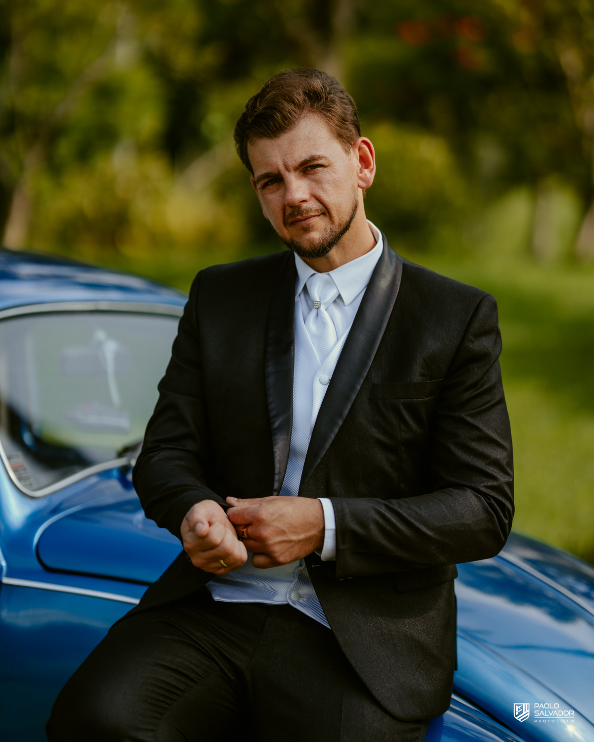Noivo Rogério apoiado em Fusca azul clássico durante making of no Sítio Colina Verde em Indaial, carro antigo com valor emocional, ensaio de noivo criativo, fotografia de casamento em Indaial Santa Catarina