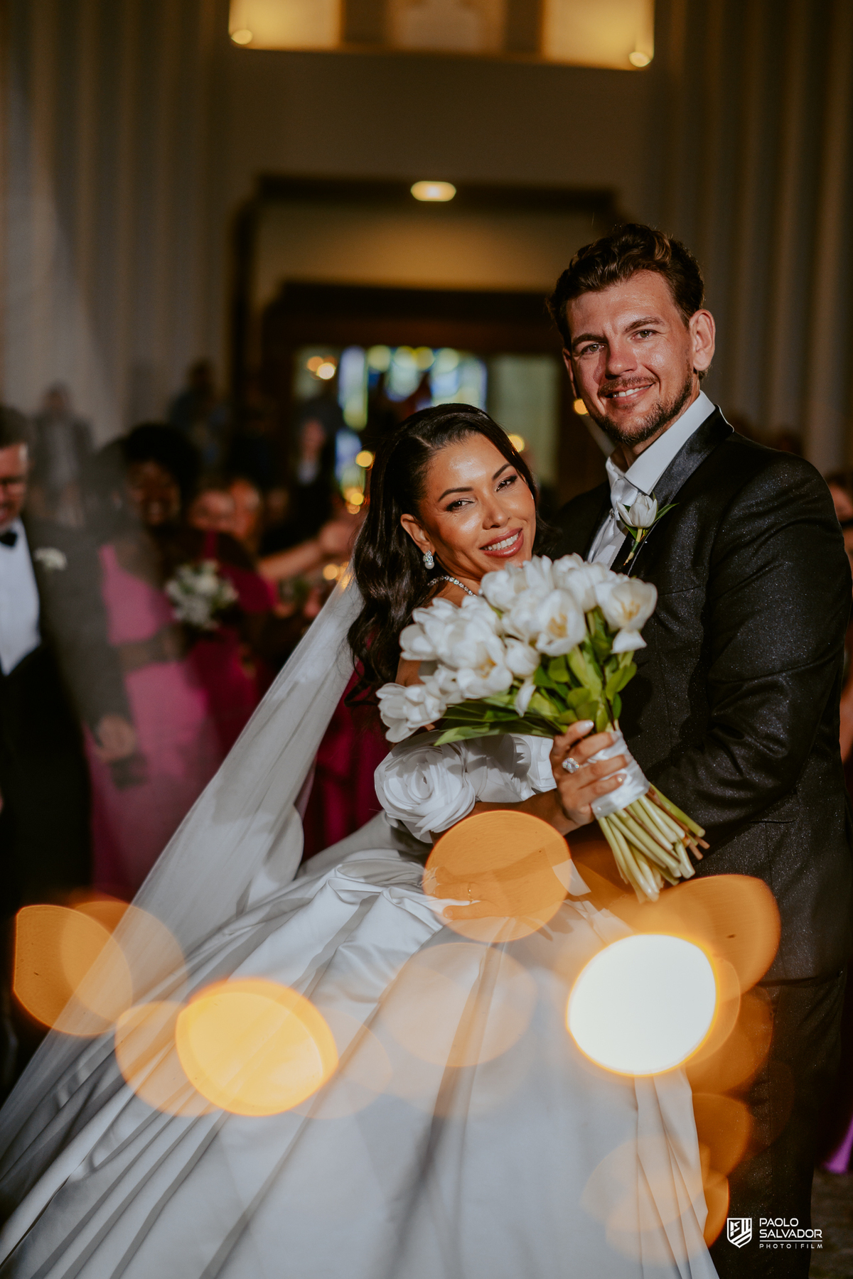 Saída dos noivos com sparkles em frente à Igreja Santa Inês em Indaial, beijo do casal, fotografia de casamento noturno cinematográfico