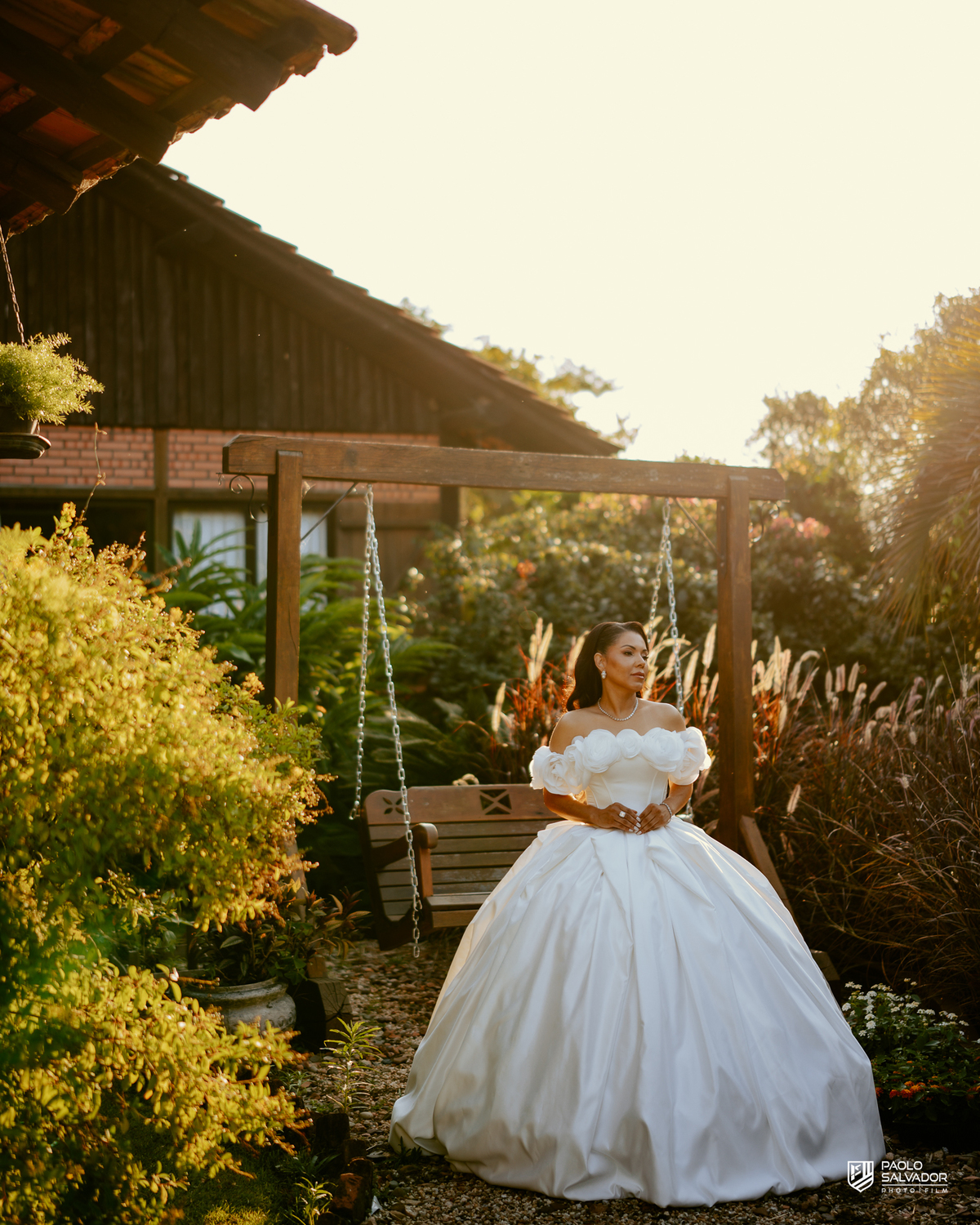 Noiva com vestido de luxo em ensaio na decoração externa com luz dourada, Sociedade Recreativa Indaial, tendência ensaio noiva pronta, fotografia de casamento premium Santa Catarina