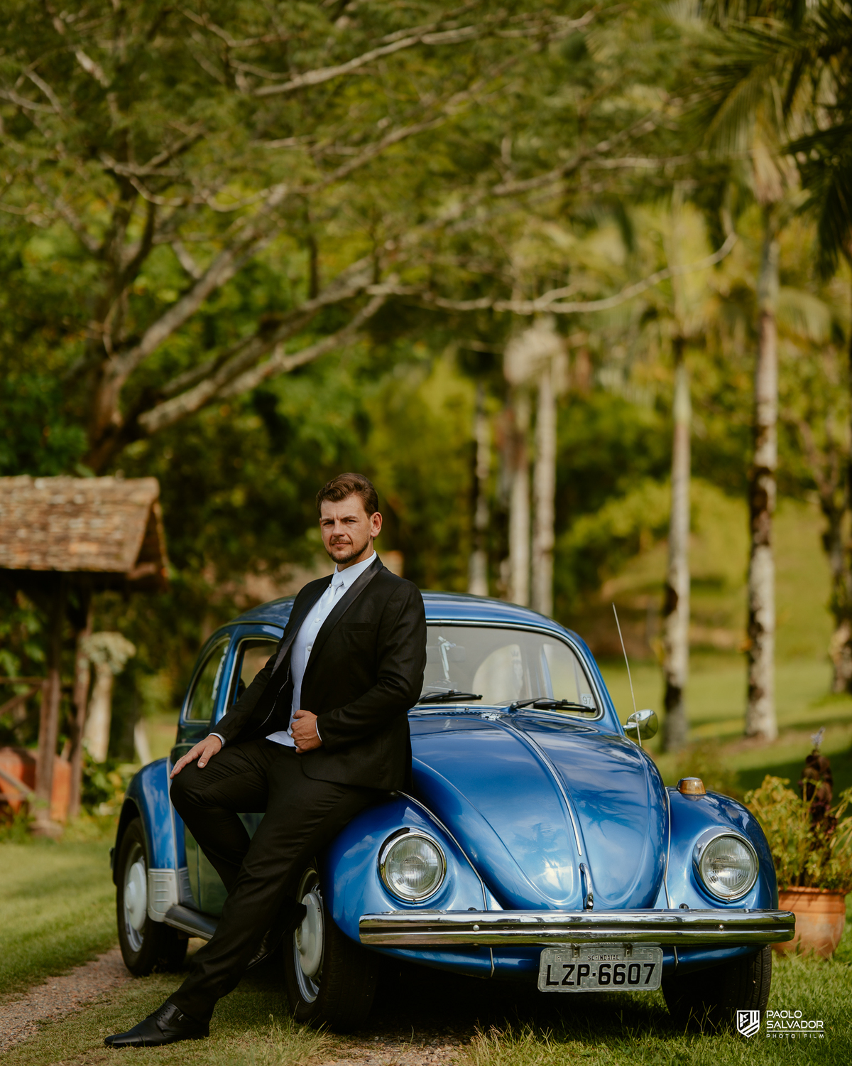 Noivo Rogério apoiado em Fusca azul clássico durante making of no Sítio Colina Verde em Indaial, carro antigo com valor emocional, ensaio de noivo criativo, fotografia de casamento em Indaial Santa Catarina