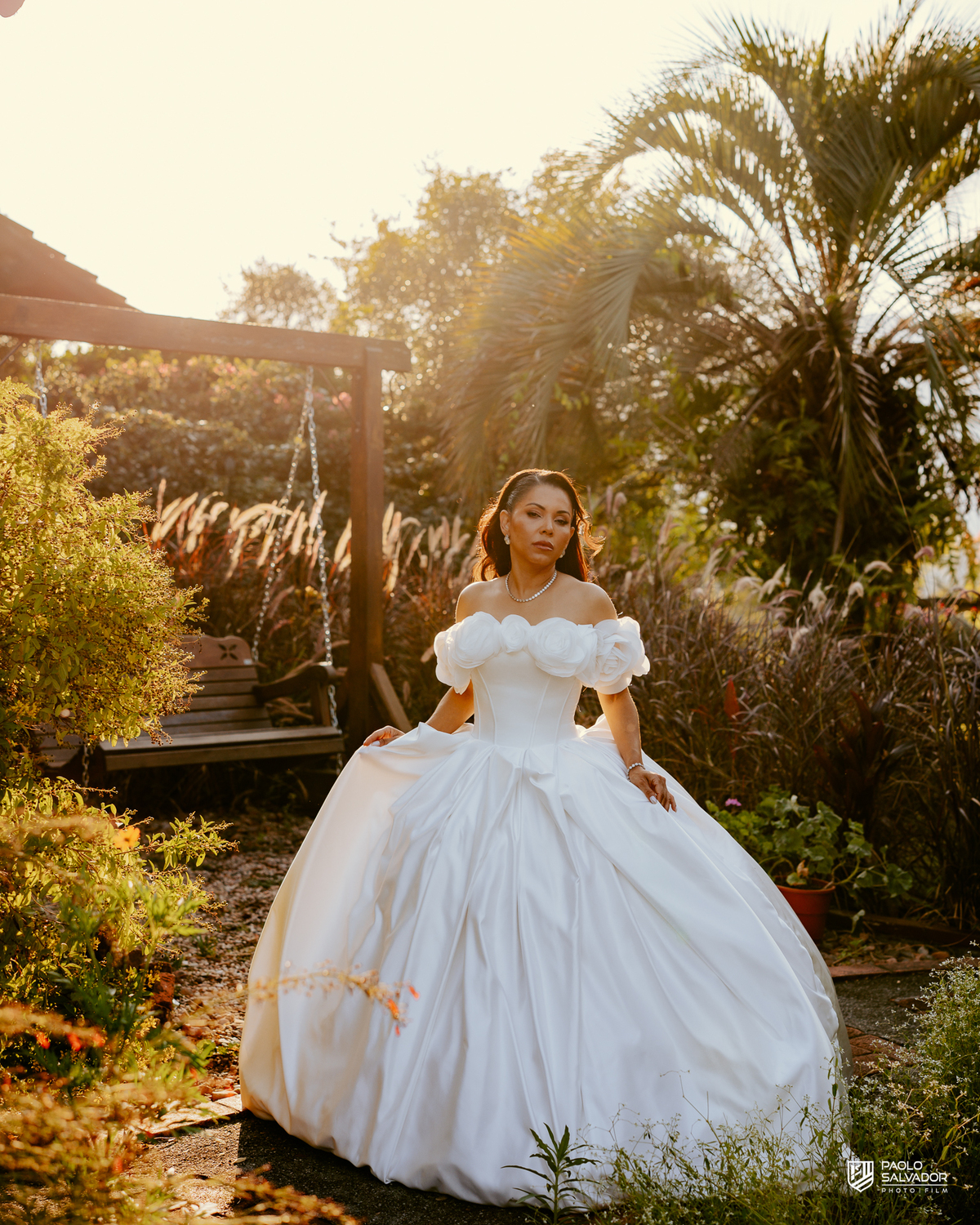 Noiva com vestido de luxo em ensaio na decoração externa com luz dourada, Sociedade Recreativa Indaial, tendência ensaio noiva pronta, fotografia de casamento premium Santa Catarina