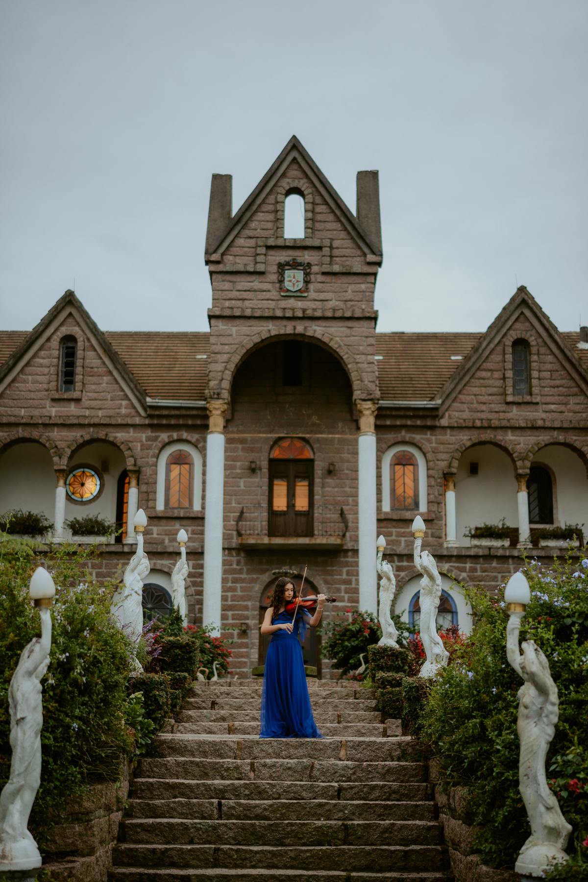 Ensaio de 15 anos debutante no Castelo Belvedere em 13 de Maio Santa Catarina, fotos de debutante em jardim, escadaria, charrete e castelo, ensaio feminino elegante com vestido azul e rosa, fotografia profissional de 15 anos com vestido princesa 