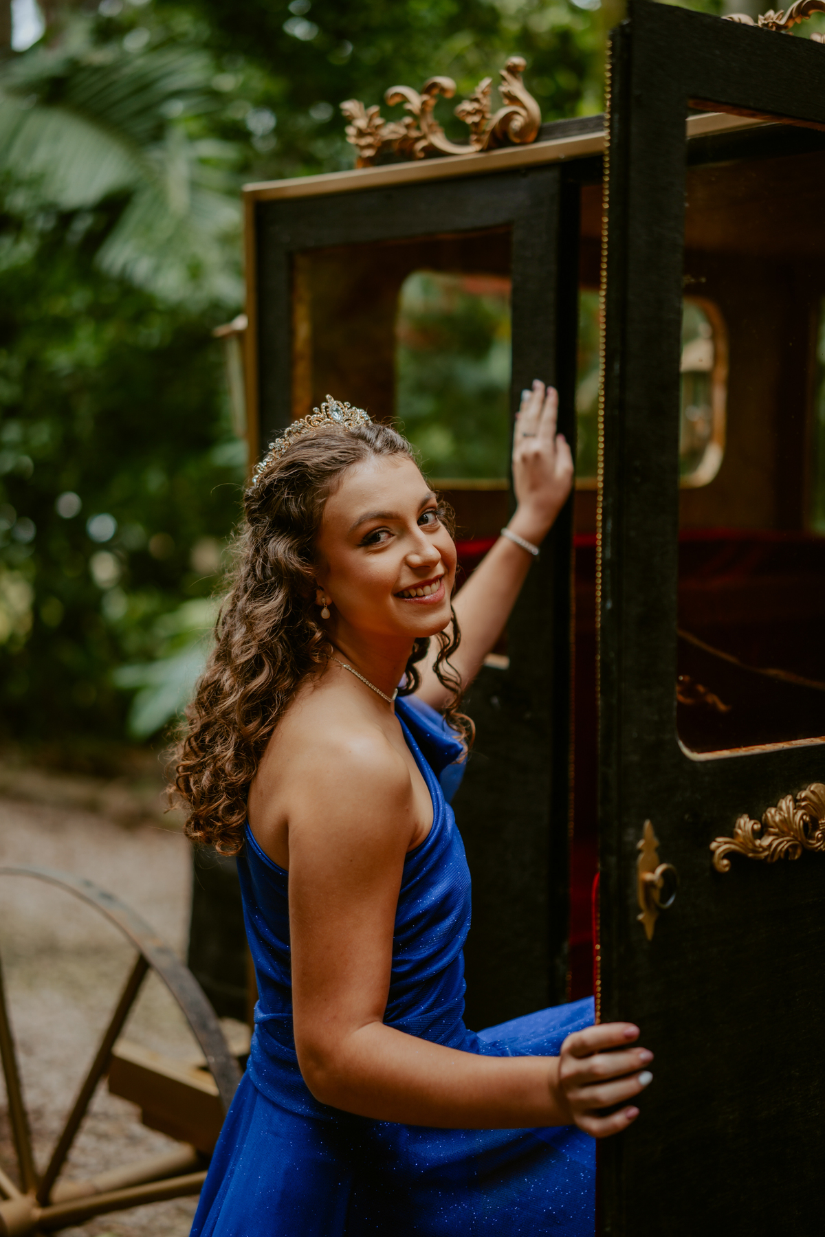 Ensaio de 15 anos debutante no Castelo Belvedere em 13 de Maio Santa Catarina, fotos de debutante em jardim, escadaria, charrete e castelo, ensaio feminino elegante com vestido azul e rosa, fotografia profissional de 15 anos na carruagem de princesa 