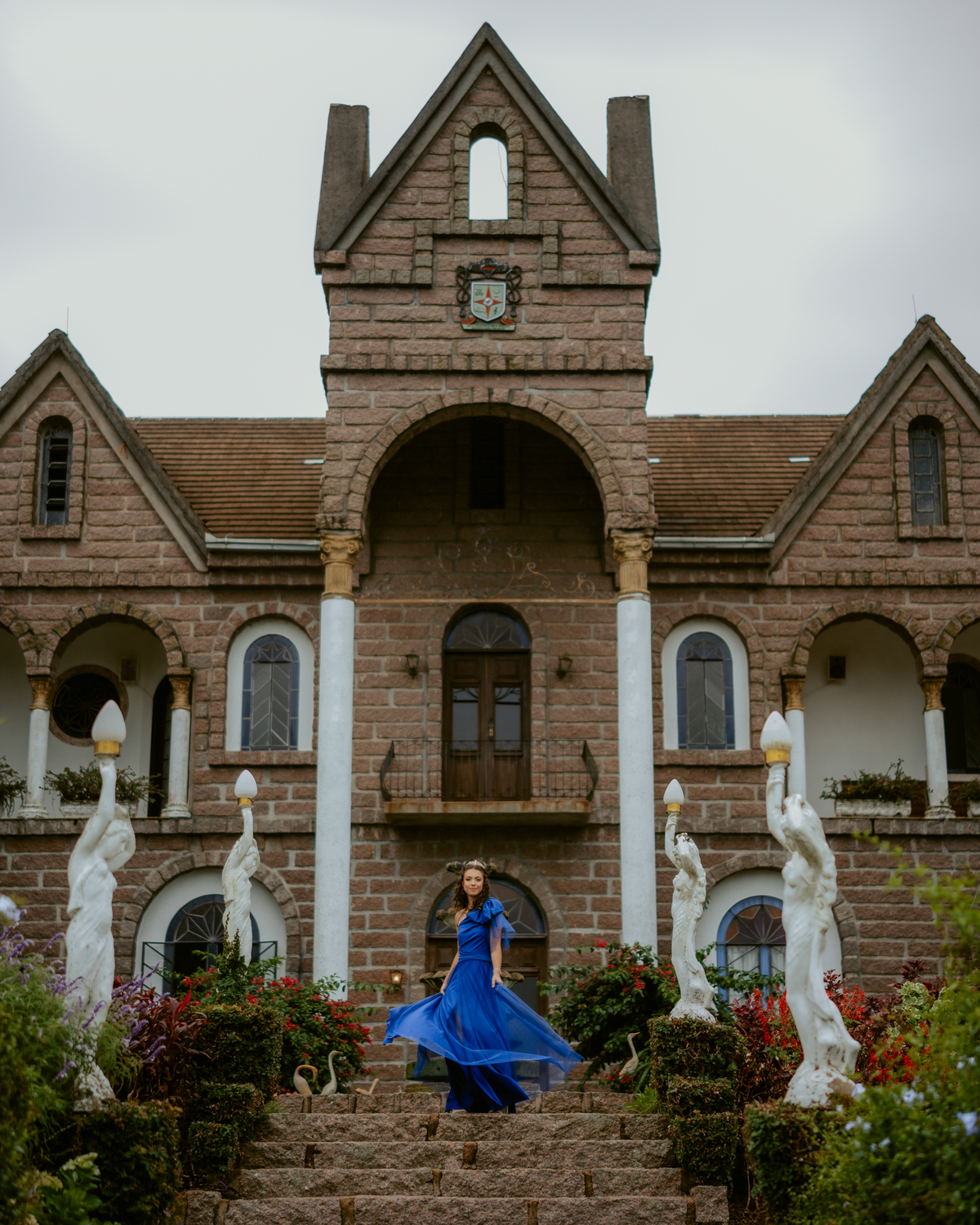 Ensaio de 15 anos debutante no Castelo Belvedere em 13 de Maio Santa Catarina, fotos de debutante em jardim, escadaria, charrete e castelo, ensaio feminino elegante com vestido azul e rosa, fotografia profissional de 15 anos com vestido princesa 