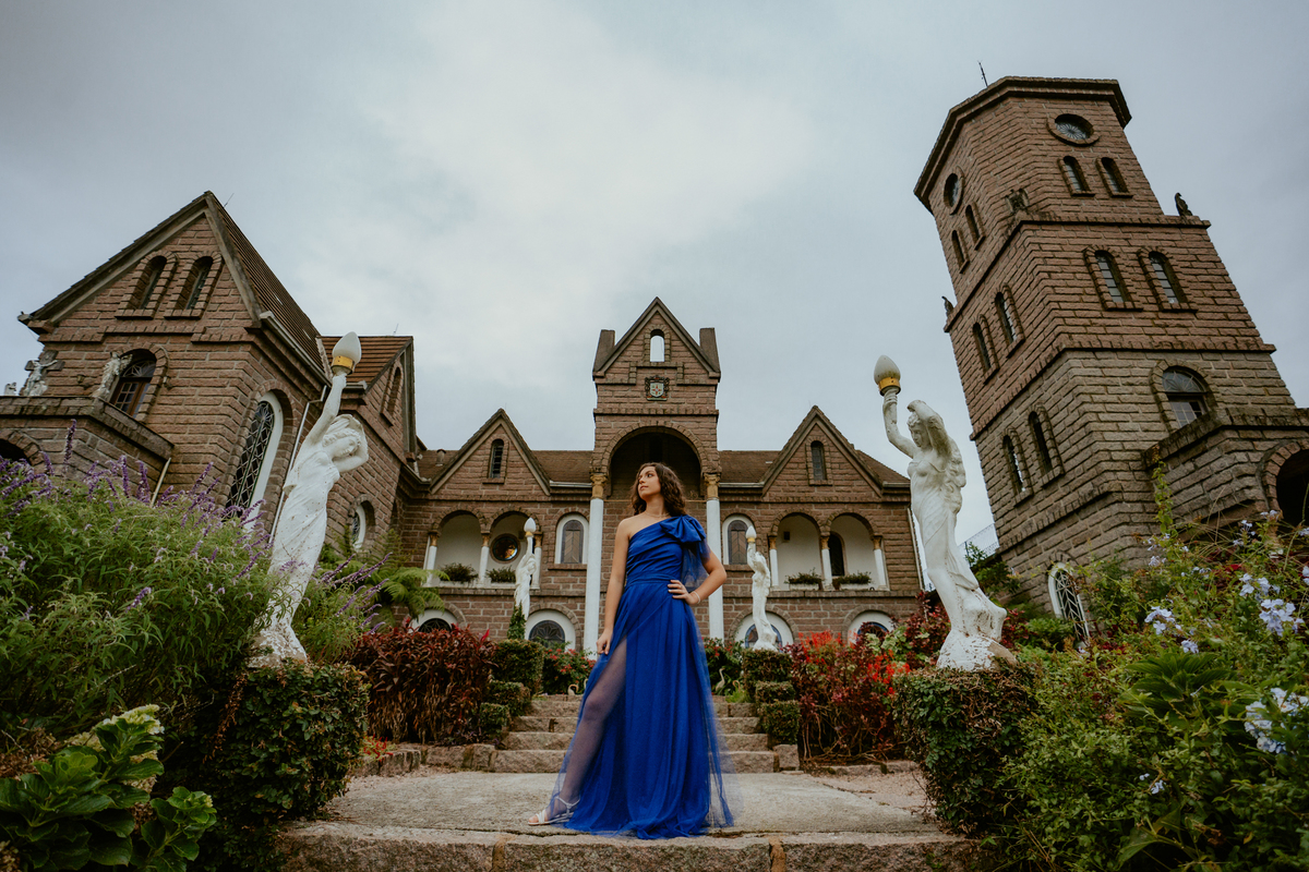 Ensaio de 15 anos debutante no Castelo Belvedere em 13 de Maio Santa Catarina, fotos de debutante em jardim, escadaria, charrete e castelo, ensaio feminino elegante com vestido azul e rosa, fotografia profissional de 15 anos com vestido princesa 