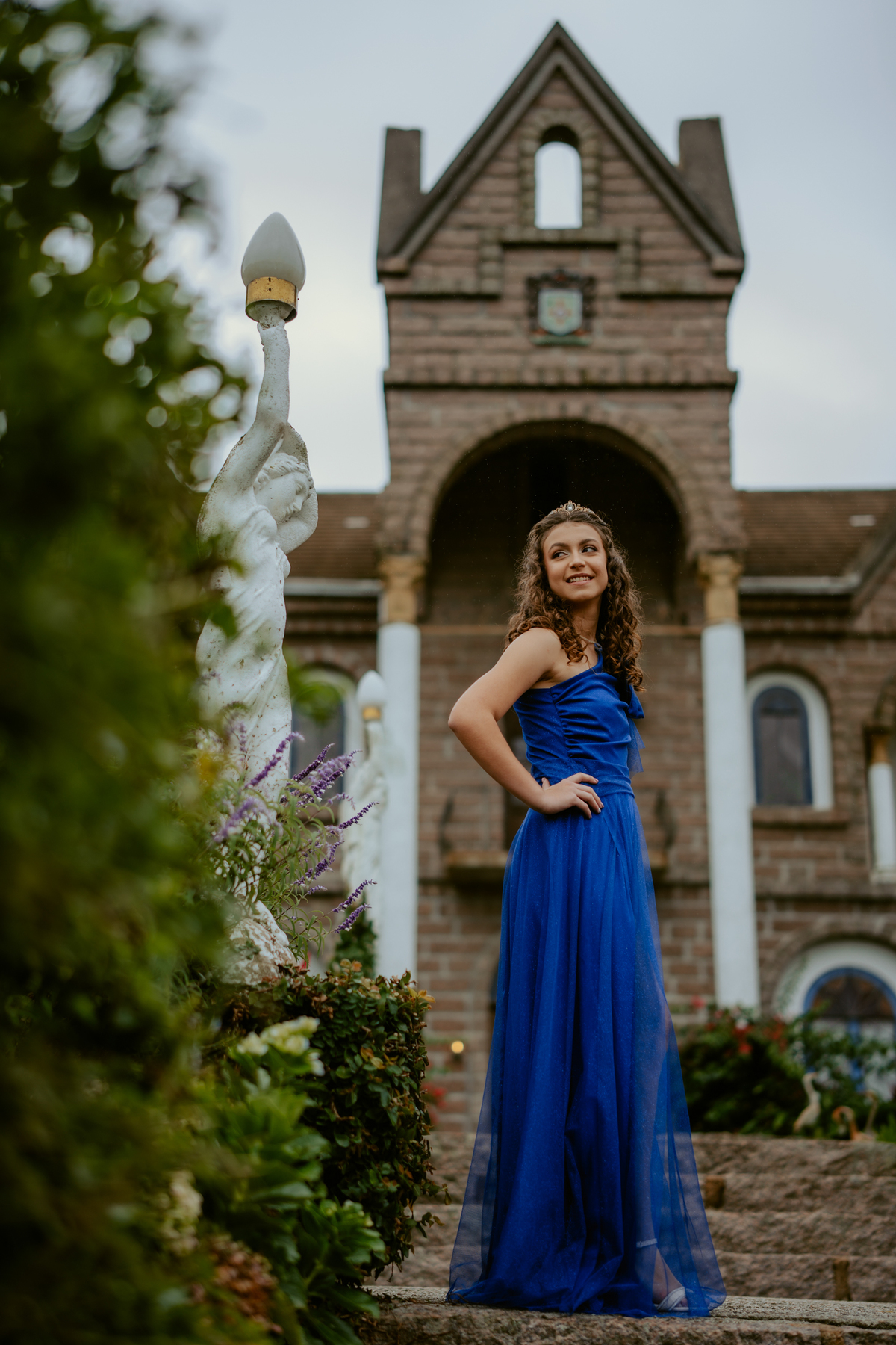 Ensaio de 15 anos debutante no Castelo Belvedere em 13 de Maio Santa Catarina, fotos de debutante em jardim, escadaria, charrete e castelo, ensaio feminino elegante com vestido azul e rosa, fotografia profissional de 15 anos com vestido princesa 