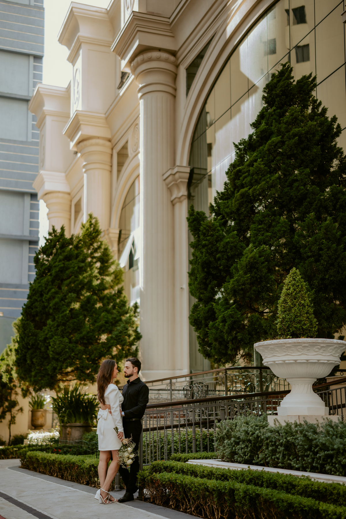 Casal em ensaio pré-wedding urbano elegante com Fusca clássico em Balneário Camboriú, cenário com fachada imponente, estilo contemporâneo e romântico, fotografia profissional com luz natural e composição sofisticada