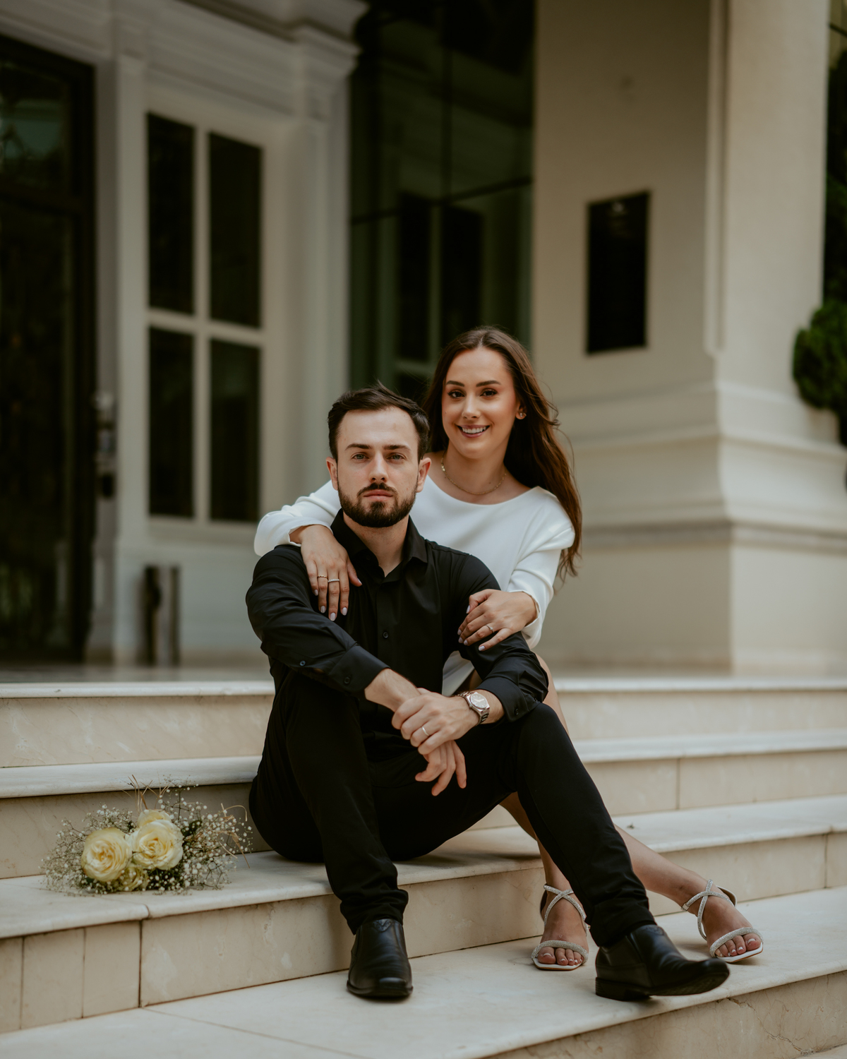 Ensaio pré-wedding ao pôr do sol na praia de Balneário Camboriú com skyline urbano ao fundo, casal brindando com champagne, estilo contemporâneo, romântico e espontâneo, fotografia profissional de casamento