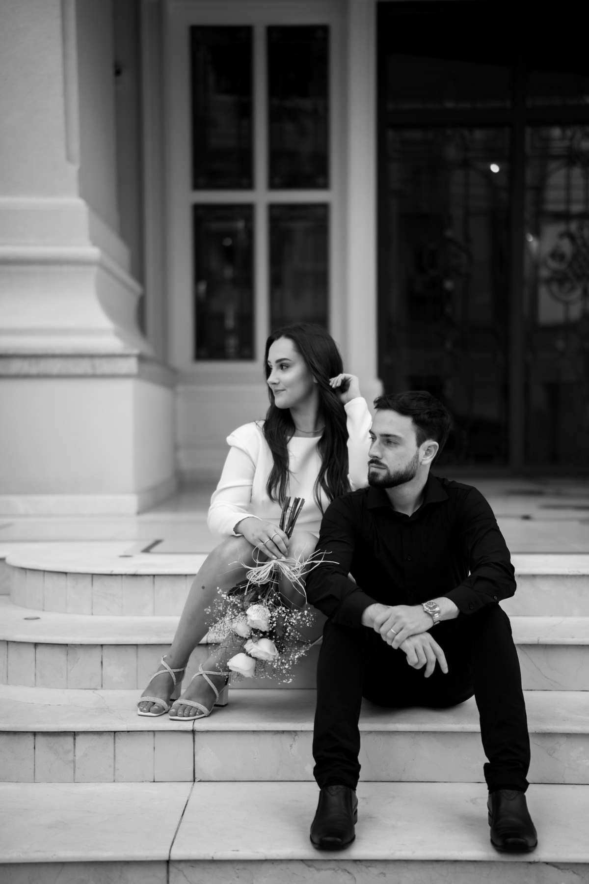 Ensaio pré-wedding ao pôr do sol na praia de Balneário Camboriú com skyline urbano ao fundo, casal brindando com champagne, estilo contemporâneo, romântico e espontâneo, fotografia profissional de casamento