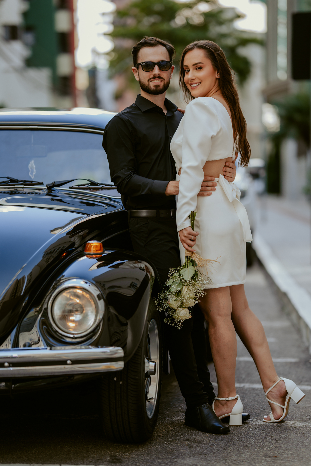 Casal apaixonado em ensaio pré-wedding com arquitetura clássica ao fundo em Balneário Camboriú, composição elegante, roupas sofisticadas preto e branco, fotografia emocional e moderna para casamento