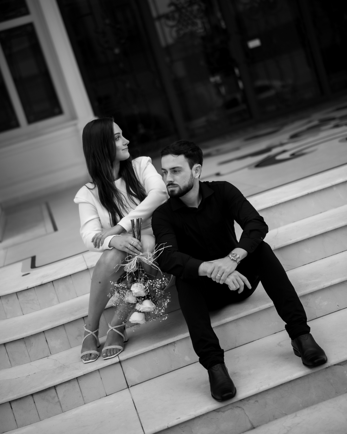 Ensaio pré-wedding ao pôr do sol na praia de Balneário Camboriú com skyline urbano ao fundo, casal brindando com champagne, estilo contemporâneo, romântico e espontâneo, fotografia profissional de casamento