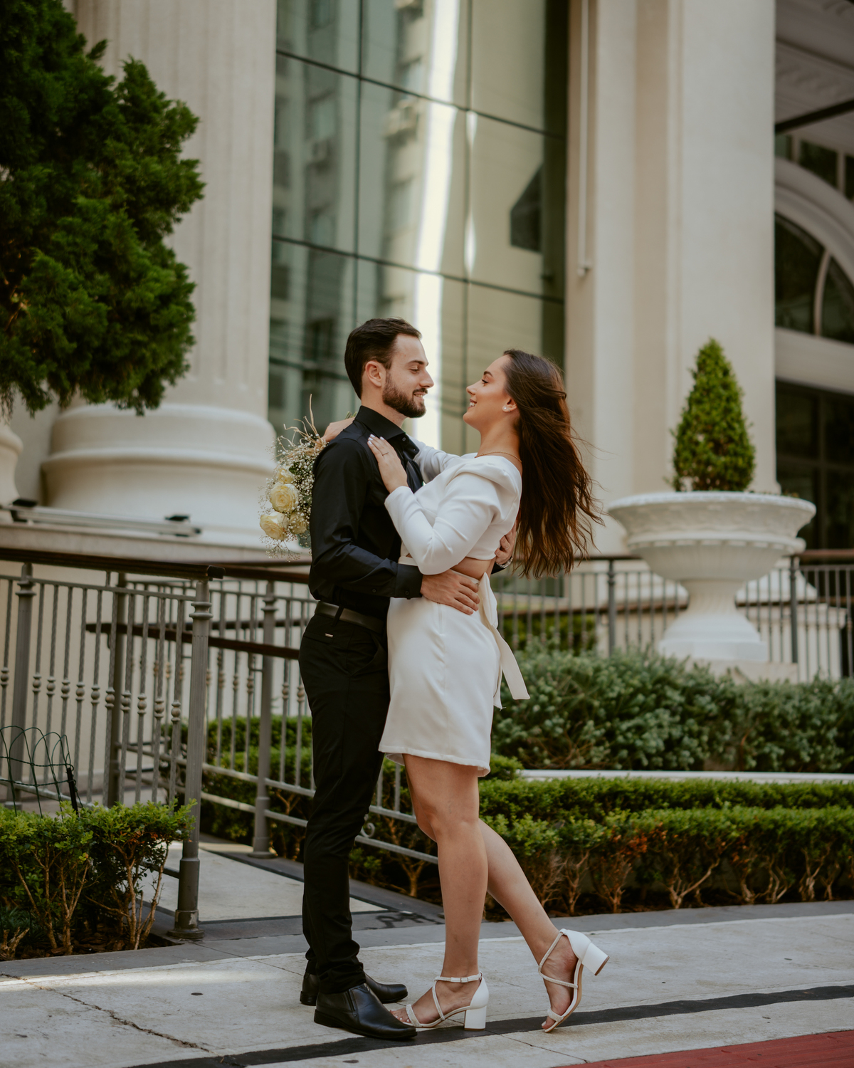 Casal em ensaio pré-wedding urbano elegante com Fusca clássico em Balneário Camboriú, cenário com fachada imponente, estilo contemporâneo e romântico, fotografia profissional com luz natural e composição sofisticada