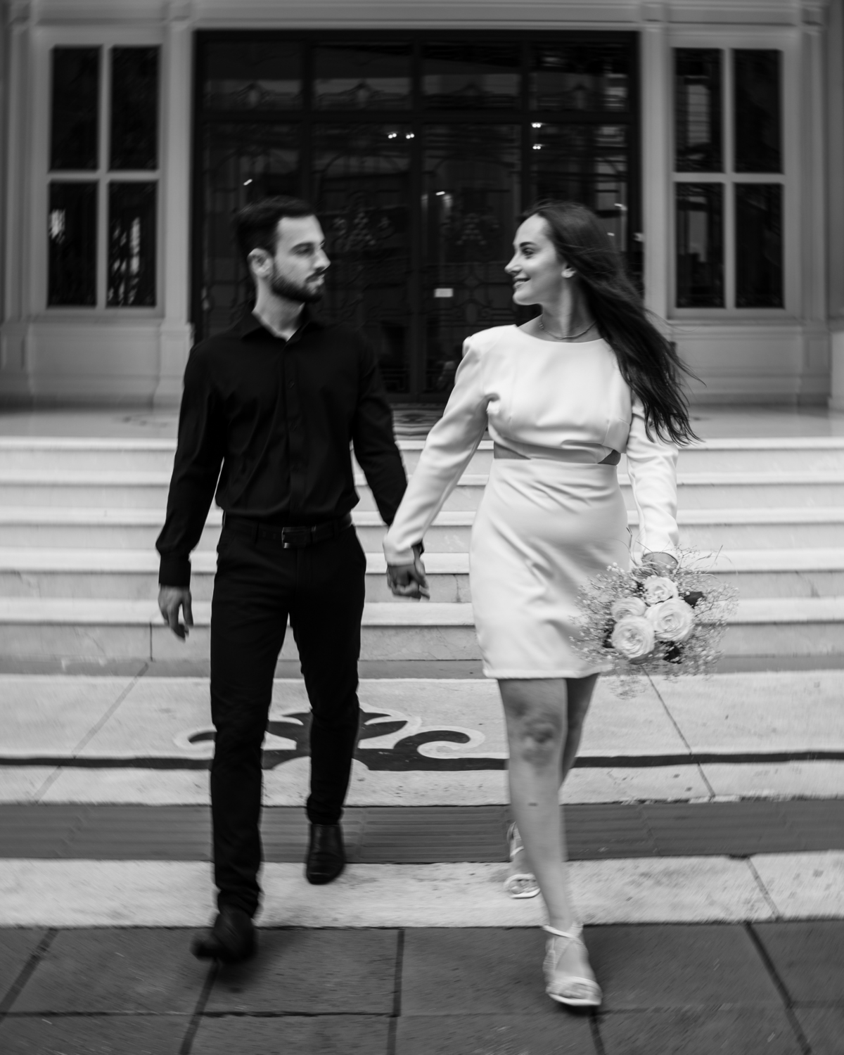 Ensaio pré-wedding ao pôr do sol na praia de Balneário Camboriú com skyline urbano ao fundo, casal brindando com champagne, estilo contemporâneo, romântico e espontâneo, fotografia profissional de casamento