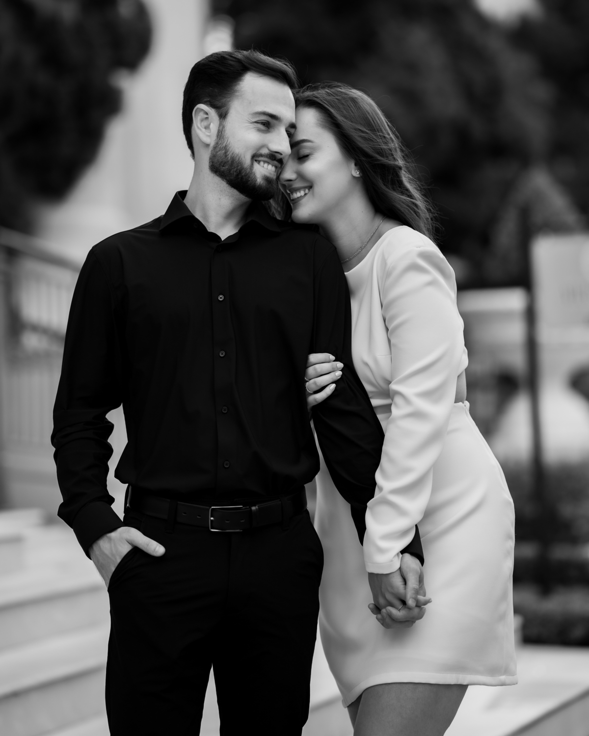 Ensaio pré-wedding na orla de Balneário Camboriú com pôr do sol entre prédios, casal sorrindo com champagne, estilo moderno e divertido, fotografia romântica com luz dourada e cenário urbano contemporâneo