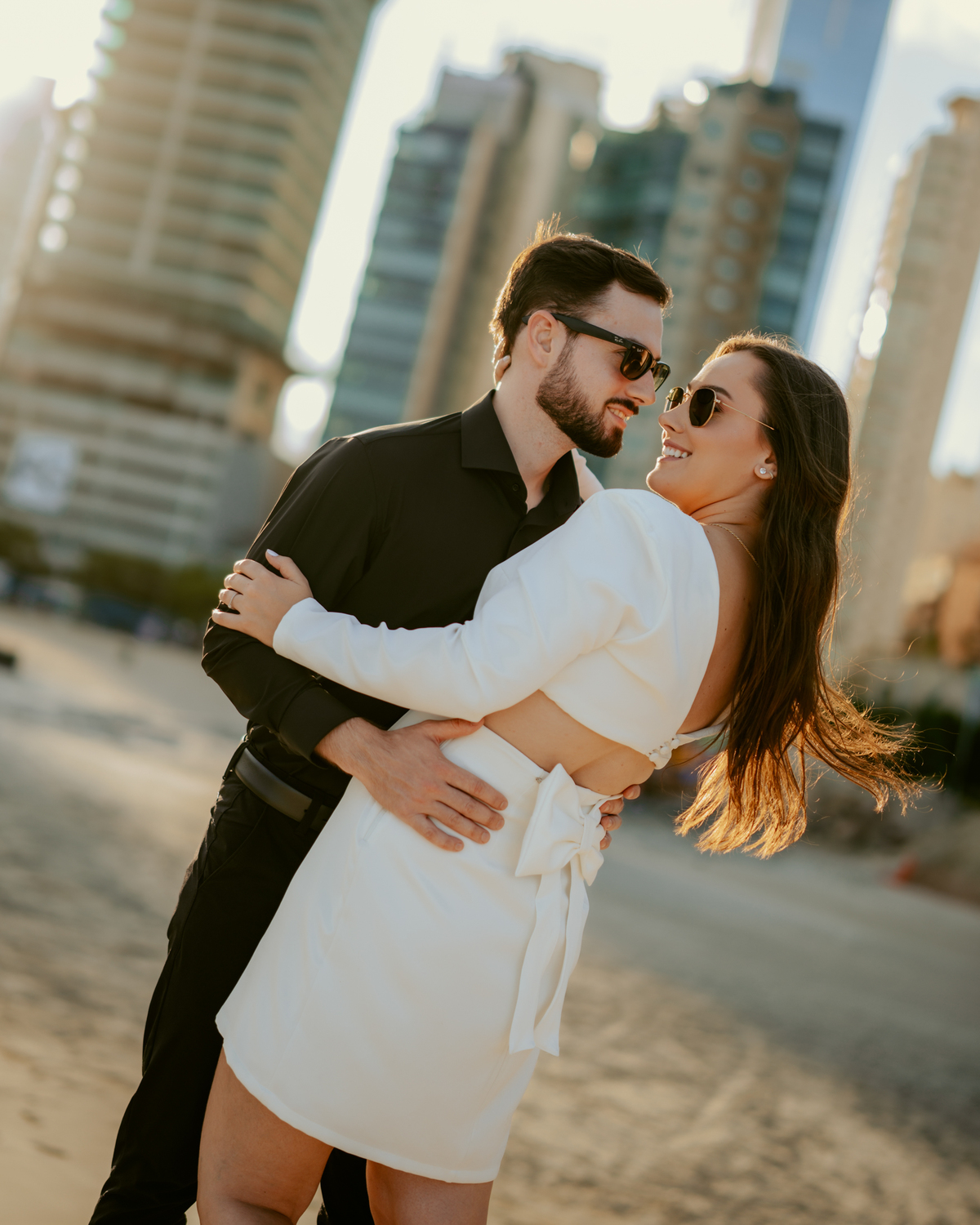 Ensaio pré-wedding de Gabi e Henrique na FG Big Wheel roda gigante de Balneário Camboriú, casal caminhando no pier da orla ao pôr do sol, fotografia urbana romântica com skyline ao fundo e luz dourada cinematográfica