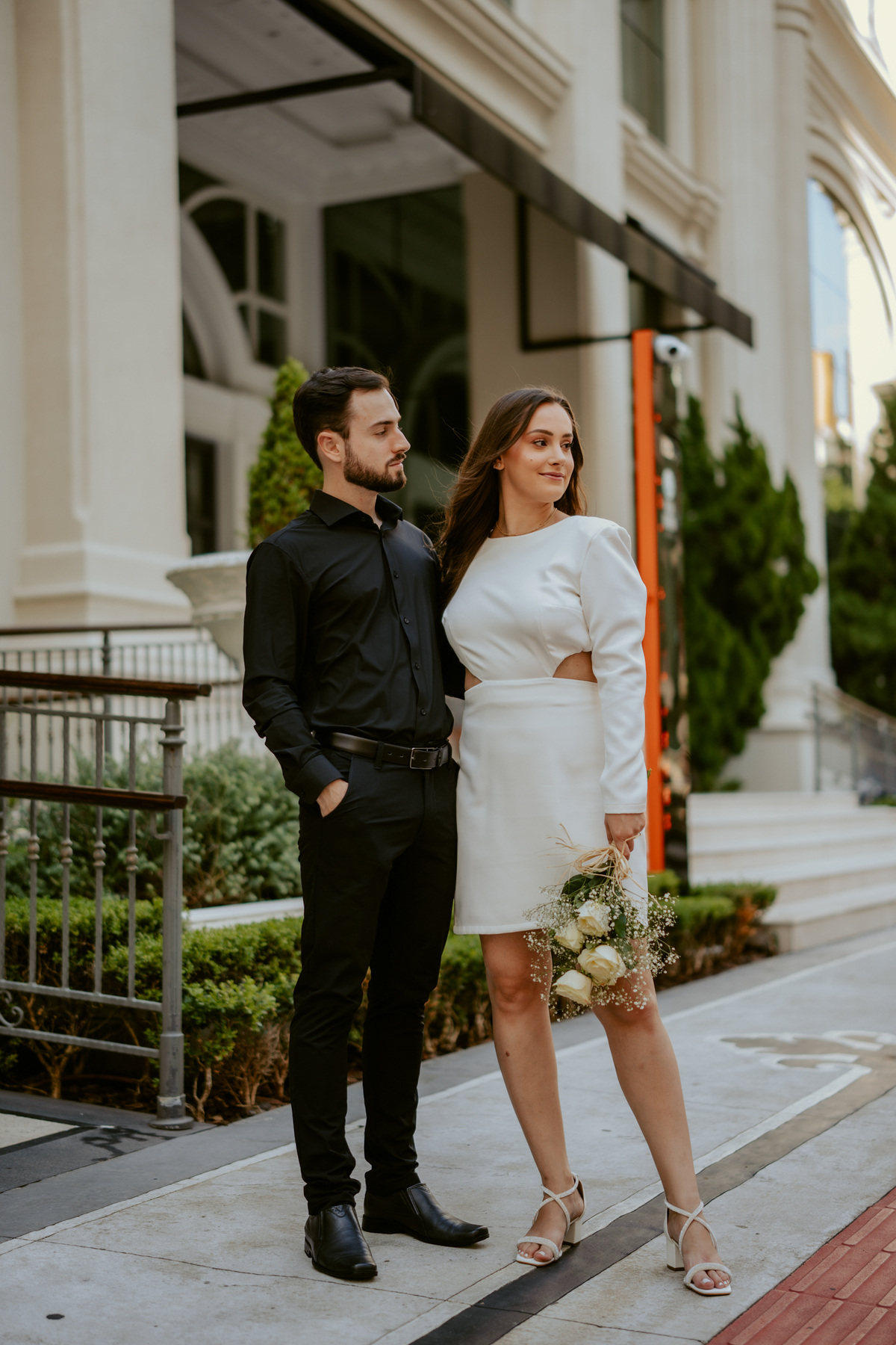 Casal em ensaio pré-wedding urbano elegante com Fusca clássico em Balneário Camboriú, cenário com fachada imponente, estilo contemporâneo e romântico, fotografia profissional com luz natural e composição sofisticada