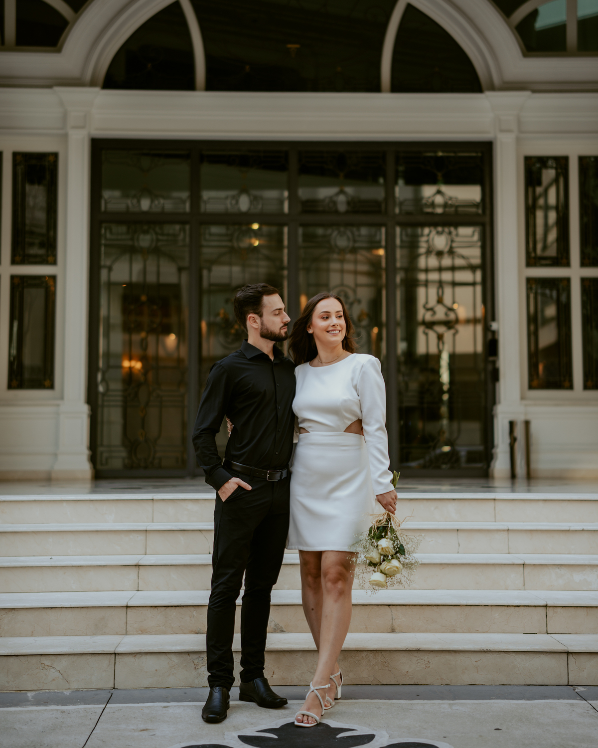 Casal em ensaio pré-wedding urbano elegante com Fusca clássico em Balneário Camboriú, cenário com fachada imponente, estilo contemporâneo e romântico, fotografia profissional com luz natural e composição sofisticada