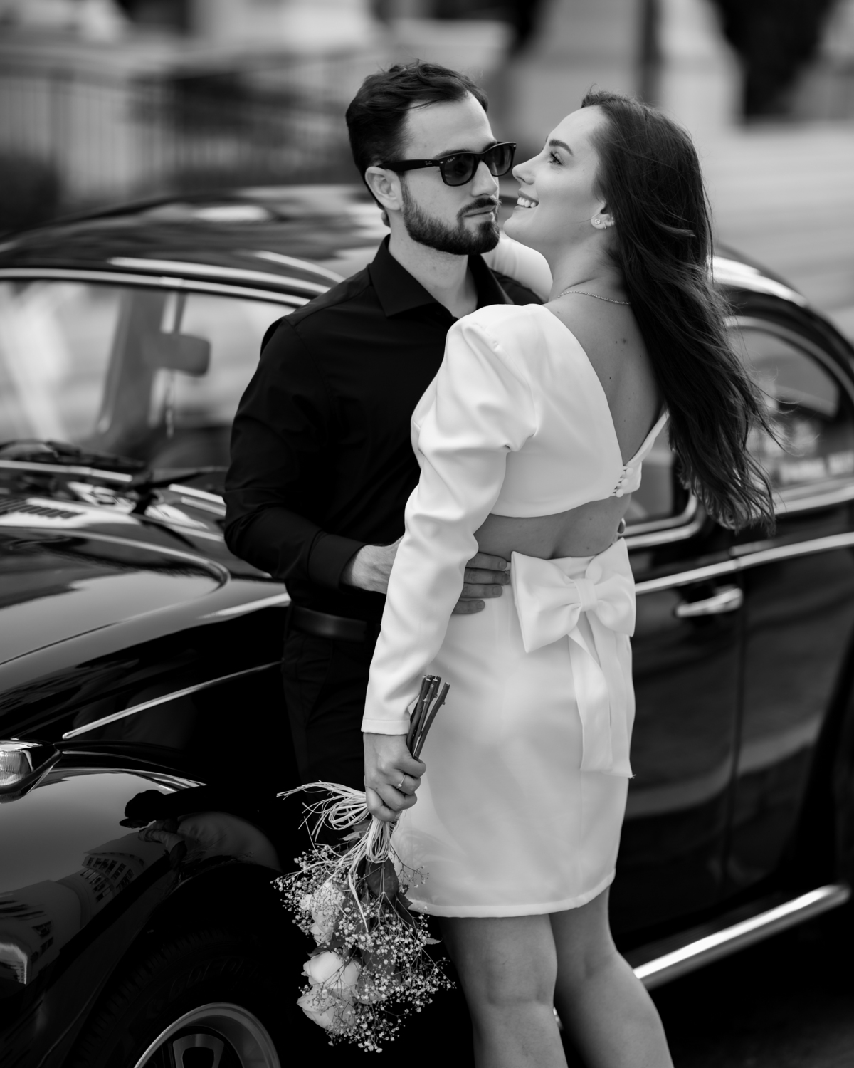 Casal apaixonado em ensaio pré-wedding com arquitetura clássica ao fundo em Balneário Camboriú, composição elegante, roupas sofisticadas preto e branco, fotografia emocional e moderna para casamento