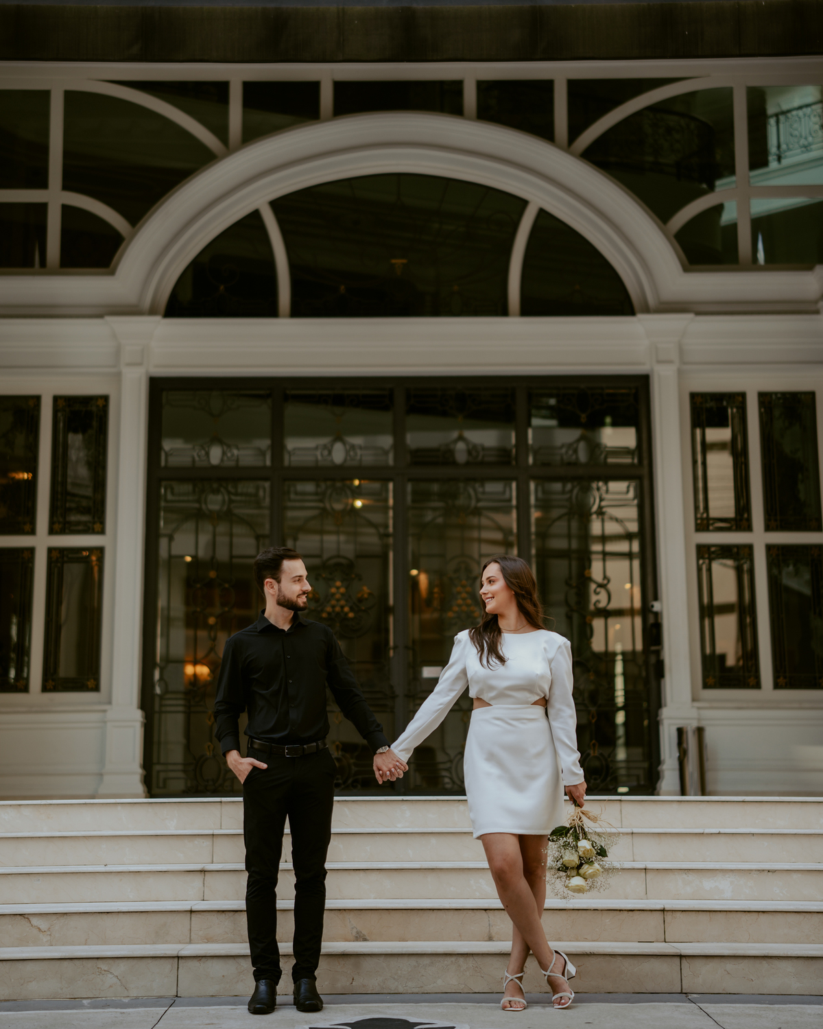 Casal em ensaio pré-wedding urbano elegante com Fusca clássico em Balneário Camboriú, cenário com fachada imponente, estilo contemporâneo e romântico, fotografia profissional com luz natural e composição sofisticada