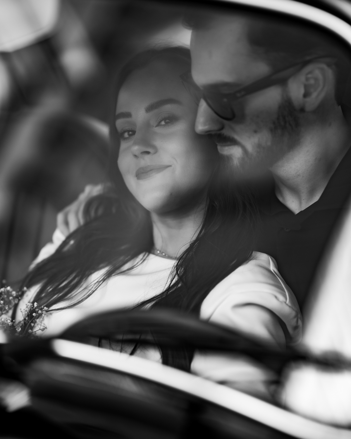 Casal apaixonado em ensaio pré-wedding com arquitetura clássica ao fundo em Balneário Camboriú, composição elegante, roupas sofisticadas preto e branco, fotografia emocional e moderna para casamento