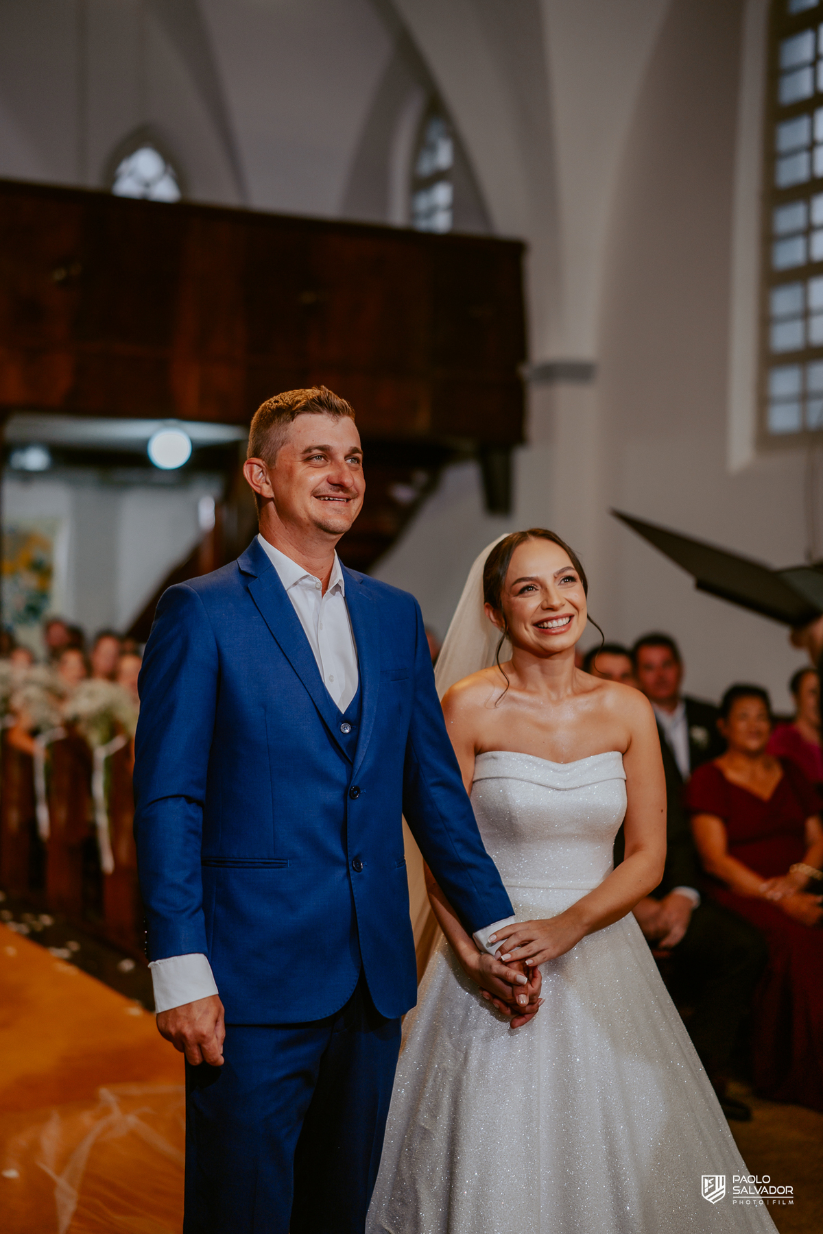 Casamento Jaque e Thayro em igreja de Massaranduba, entrada da noiva e emoção da cerimônia, fotografia de casamento clássica e documental, noivos no altar com convidados ao fundo