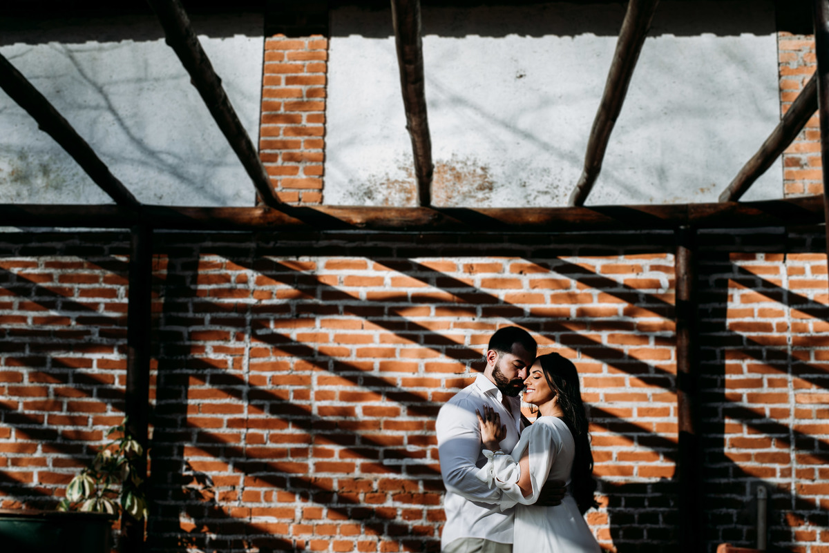 casal de noivos abraçado na sombra da parede