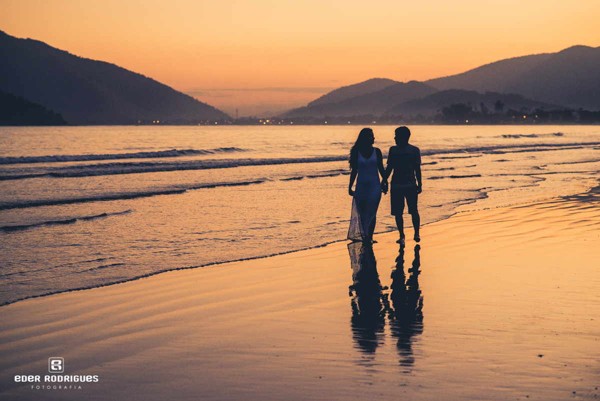 Noivos caminhando na praia em Ubatuba no pôr do sol