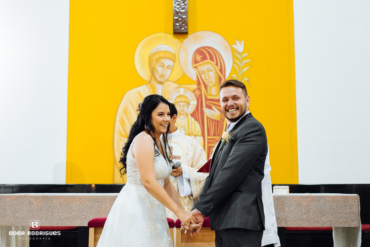 noivos sorrindo de mãos dadas na igreja sagrada familia sjc