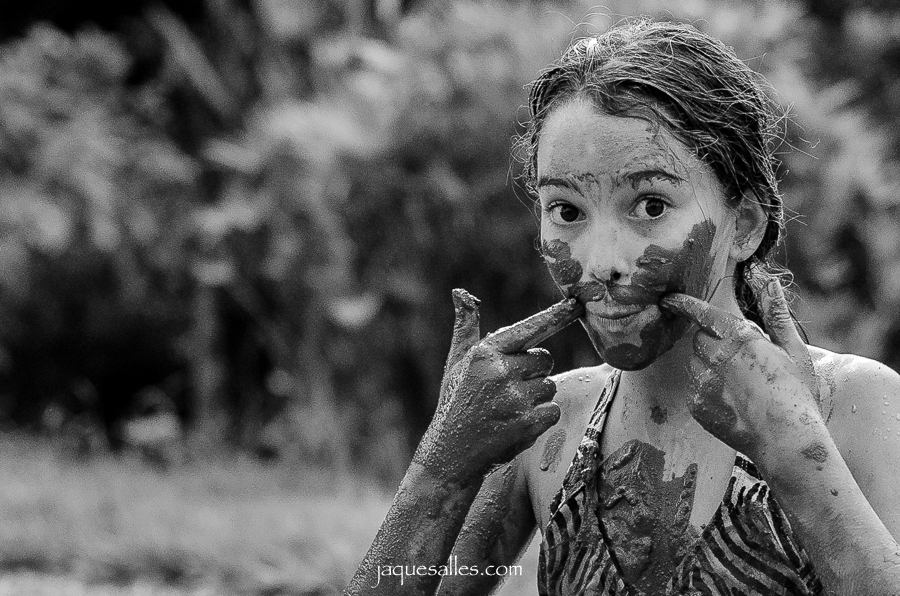 expressão genuína de uma criança que se diverte na lama e na chuva