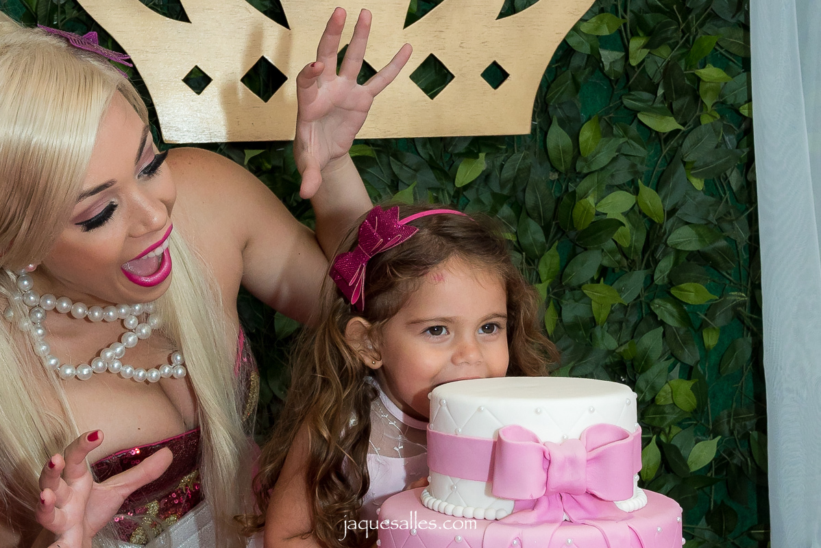 menina morde seu bolo rosa de aniversário