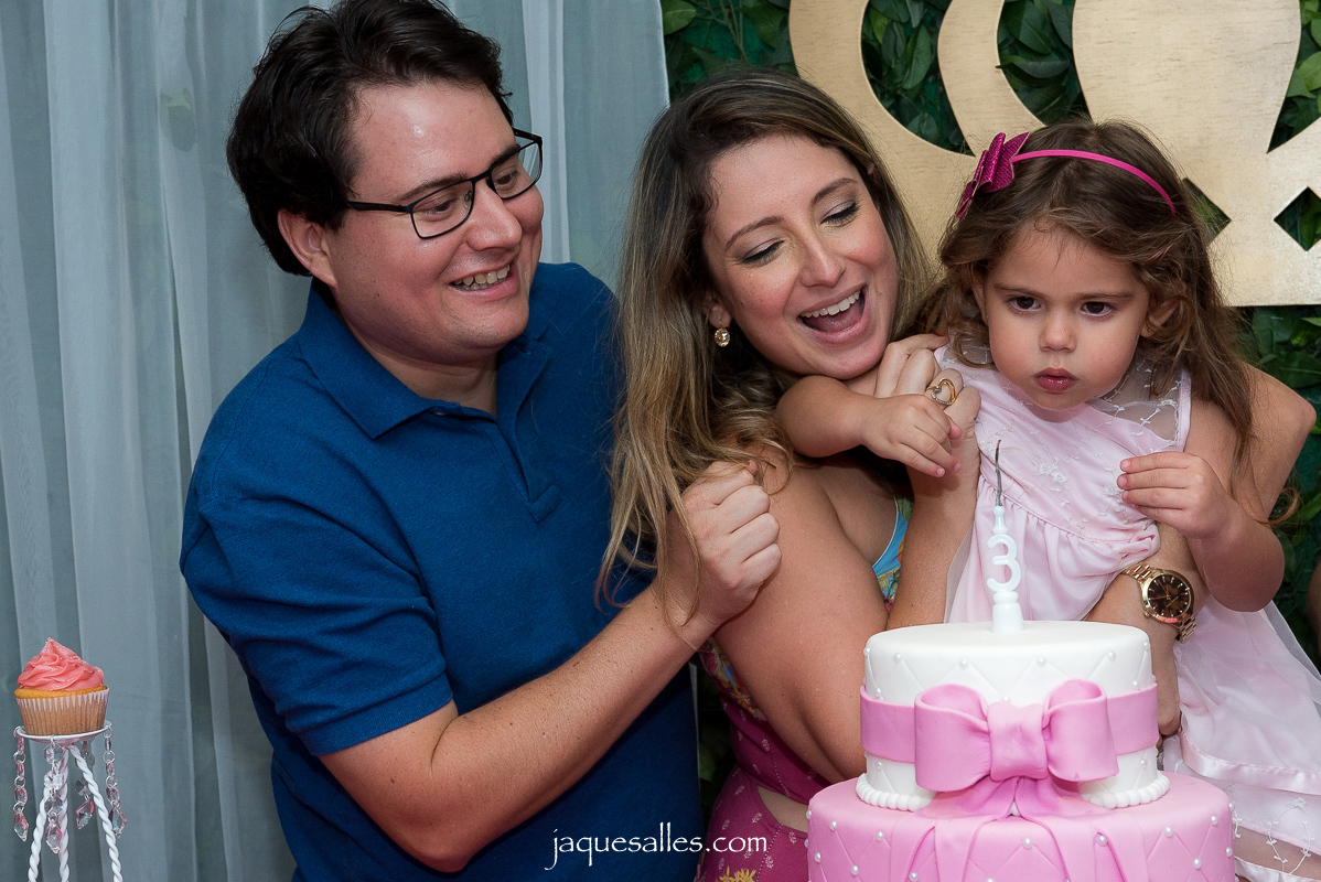 pai, mãe e filha sopram vela de aniversário