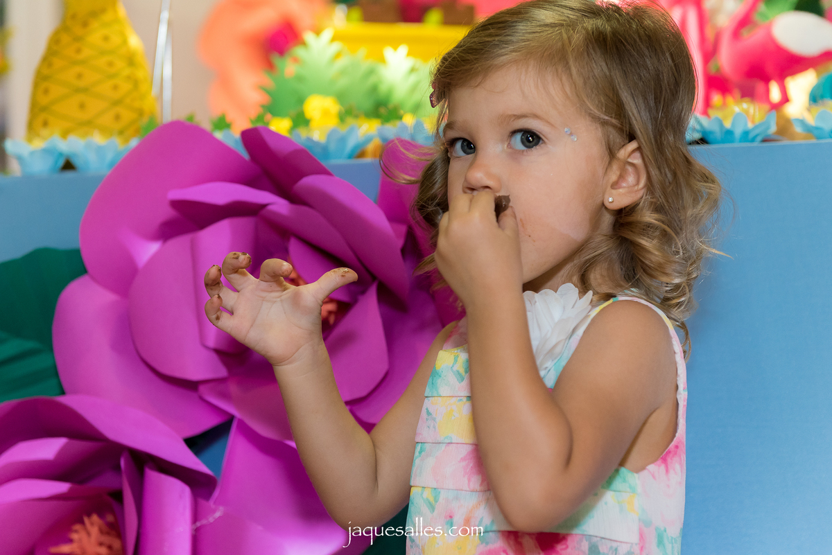 criança comendo chocolate na festa flamingo