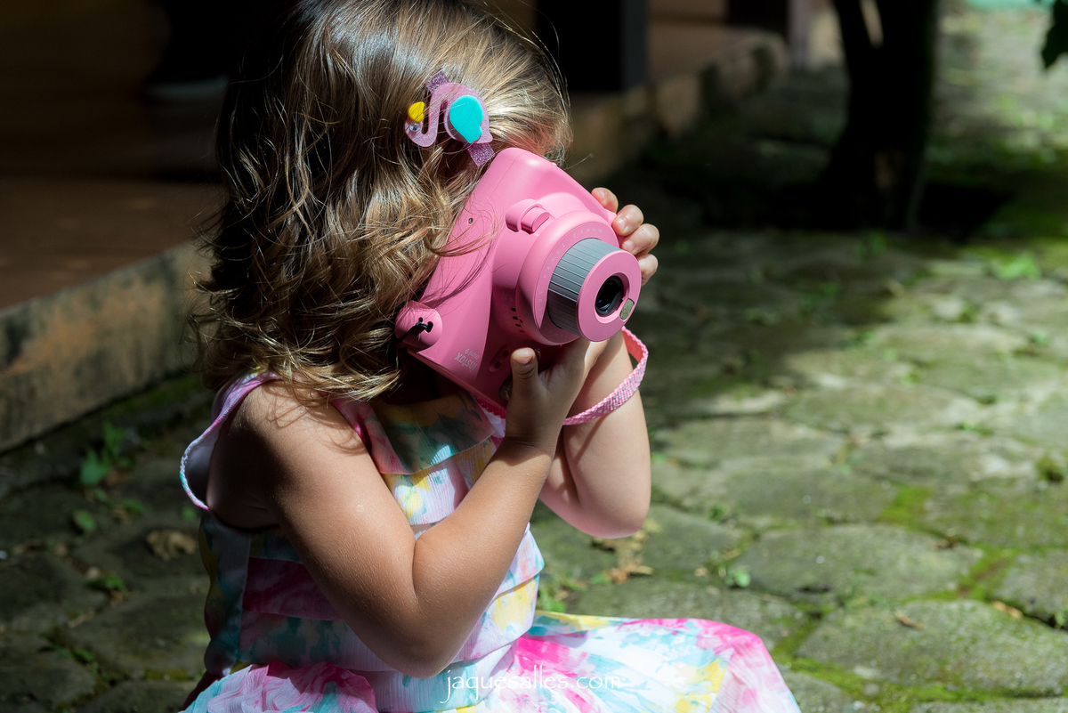 menina fotografando com câmera instax