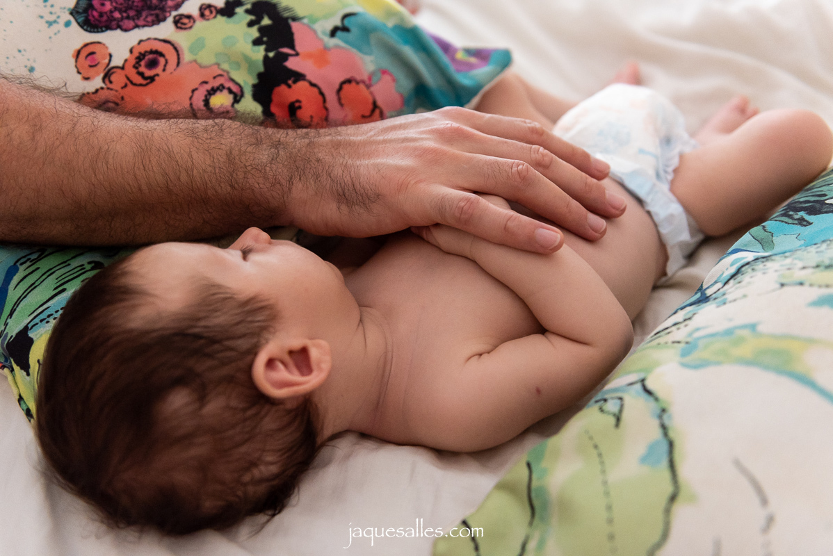 Pai colocando o bebê para dormir na cama dos pais 