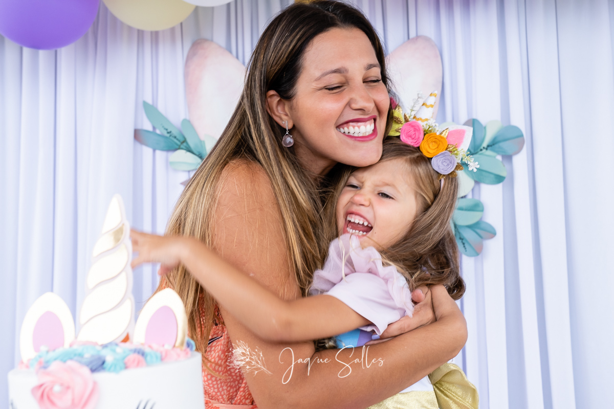 Fotografia de abraço e sorrisos entre mãe e filha registrado pela Fotógrafa Infantil Jaque Salles. A cena aconteceu em Búzios, RJ durante a Festa de Unicórnio da Maria Luiza
