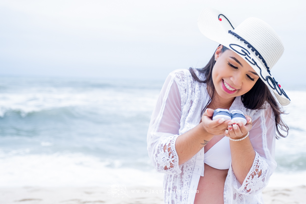 Ensaio Gestante Letícia  no Rio de Janeiro, RJ. O ensaio Fotográfico aconteceu na Prainha região do Recreio dos Bandeirantes e teve a Fotografia de Jaque Salles. Na Foto a Gestante aparece contemplando o sapatinho do bebê.