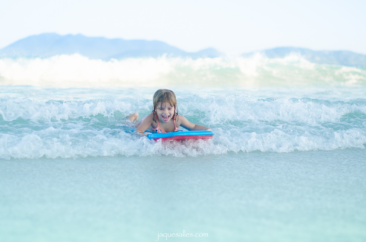 Criança surfando na praia de cabo frio na região dos lagos durante o entardecer de verão