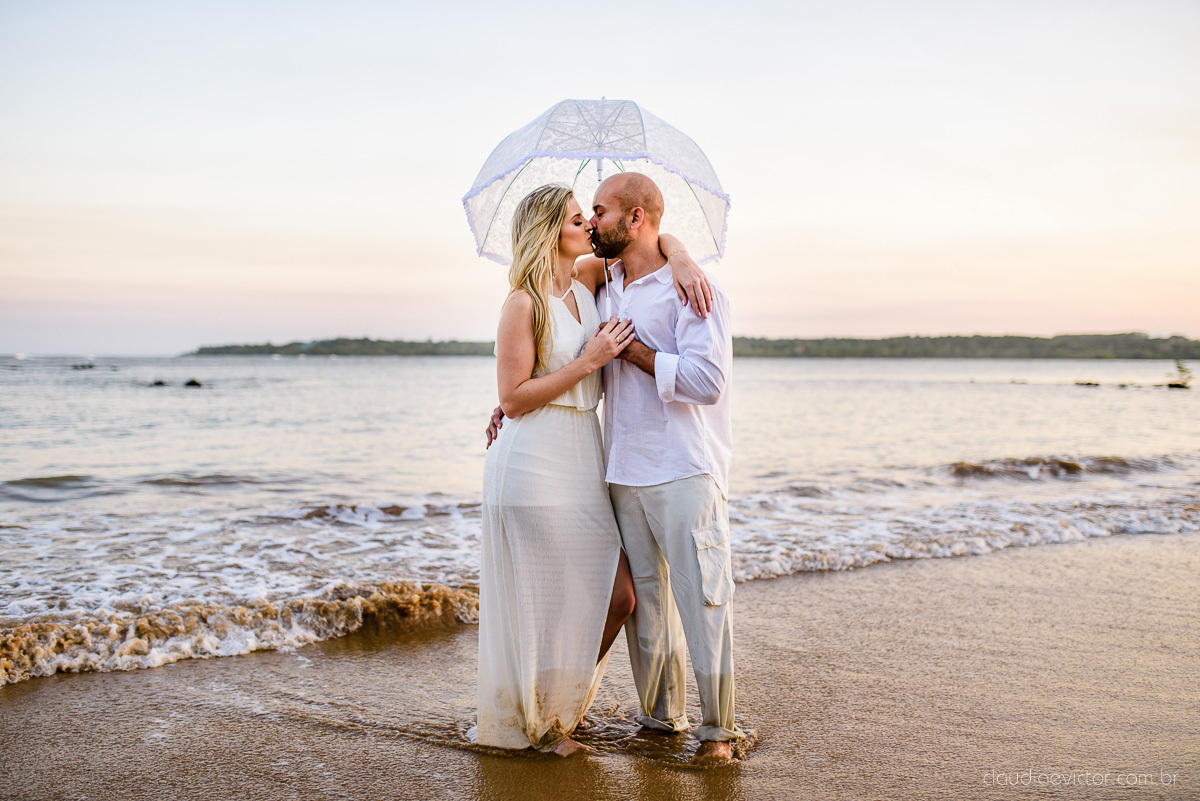 Lindo ensaio casal pre wedding com noivo e noiva na praia de coqueiral de aracruz feito por fotógrafos de casamento de vila velha fotógrafos de casamento de vitória fotógrafos de casamento de serra espirito santo es com praia, por do sol e guarda chuva