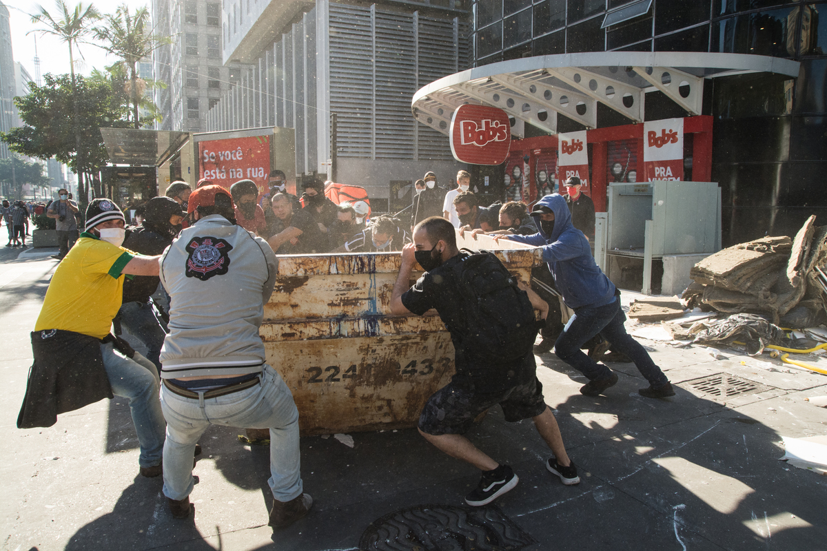 Manifestantes carregam caçamba de entulho para o meio da Av Paulista, para inibir o avanço da Policia militar na Av Paulista em 2020